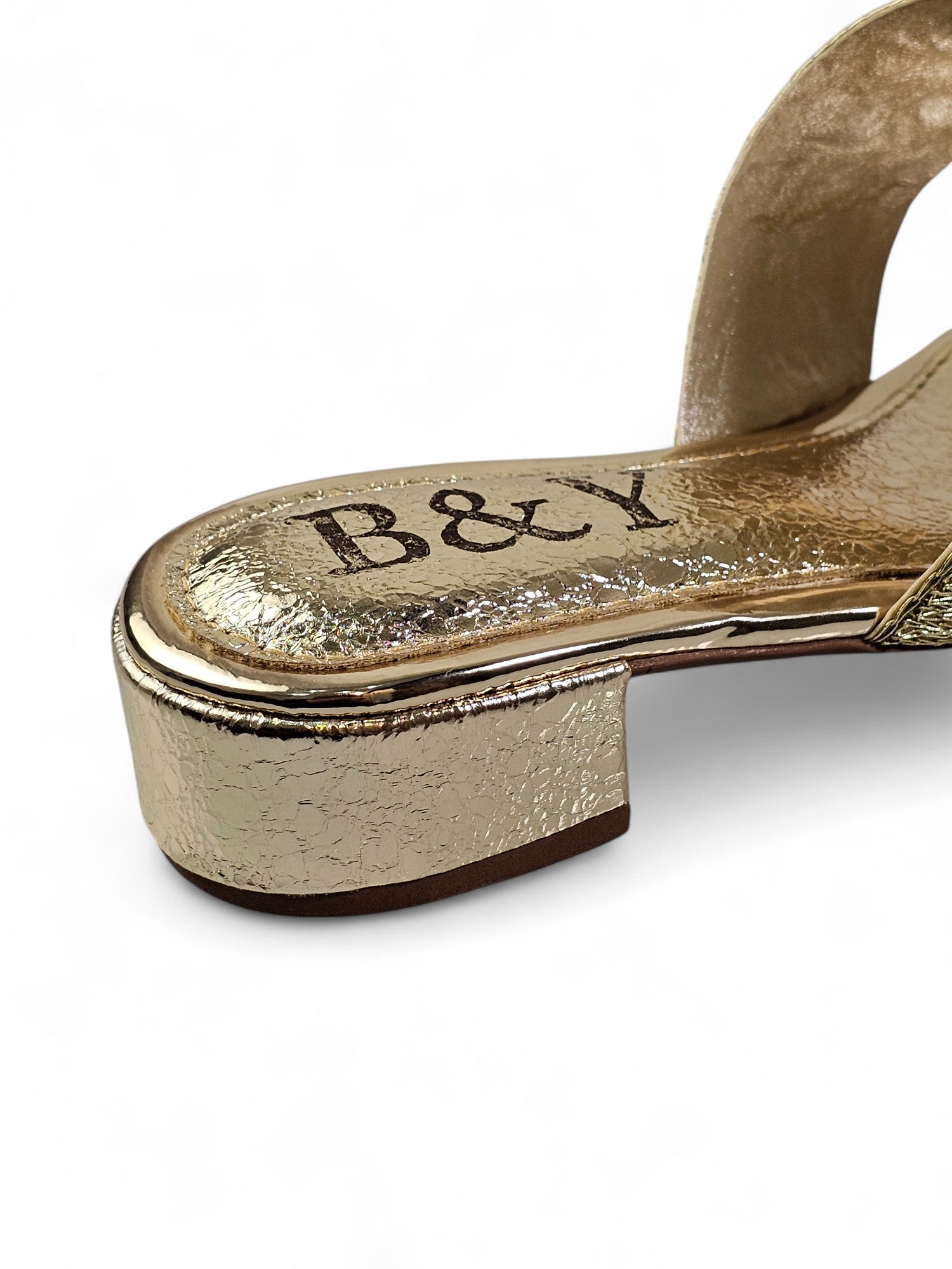 Sandália artesanal dourada com pedrarias em tons de dourado, âmbar, verde esmeralda, rubi, lilás e preto, feita à mão com salto baixo metálico espelhado.