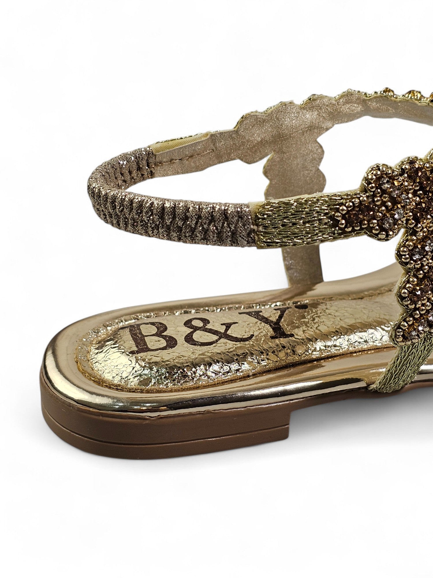 A close-up view of a pair of gold-colored sandals with a metallic, textured sole.