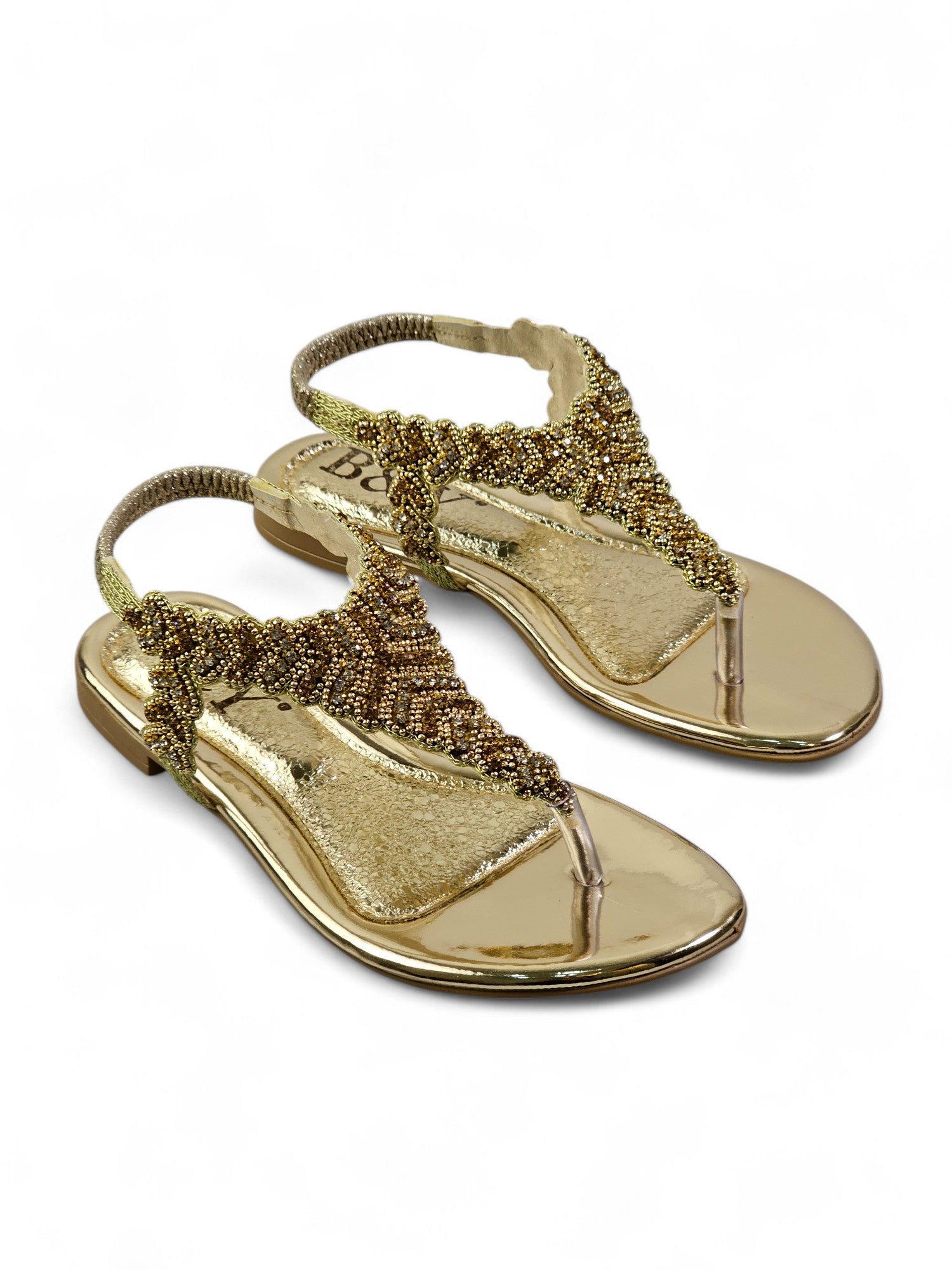 A pair of gold-colored, embellished sandals with intricate beaded designs.
