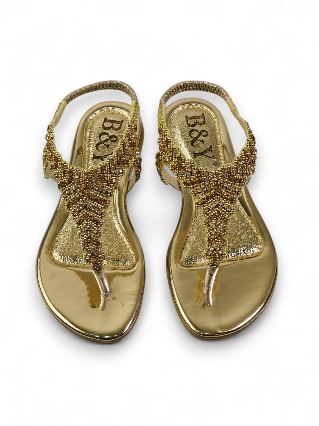 A pair of gold-colored, beaded sandals with a metallic, embellished design.
