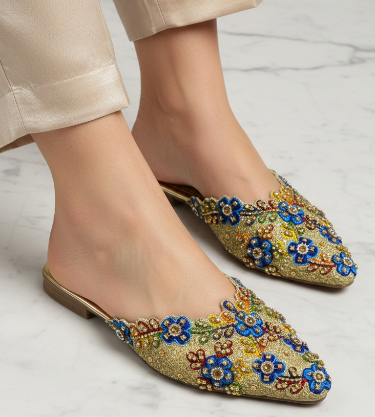 Mule artesanal dourada com bordado floral multicolorido feito à mão e pedrarias brilhantes.