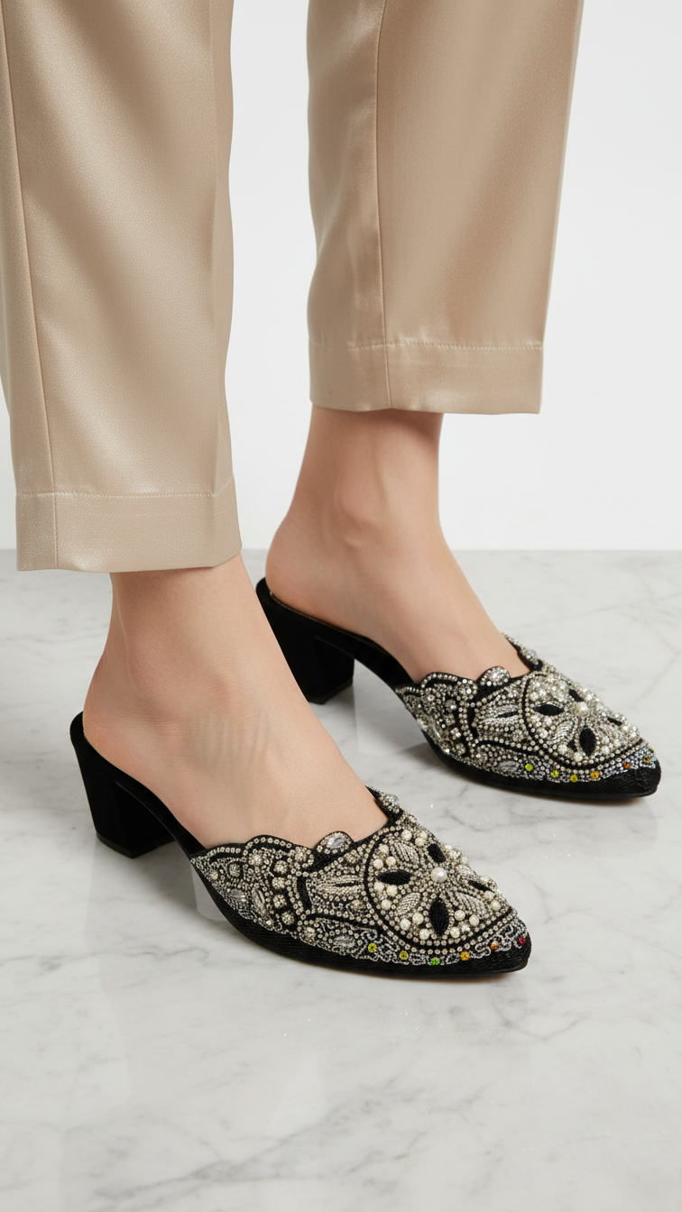 Mule artesanal B&Y preto com bordados manuais em pérolas, pedrarias e fios metálicos prateados e dourados, design geométrico floral e salto médio.
