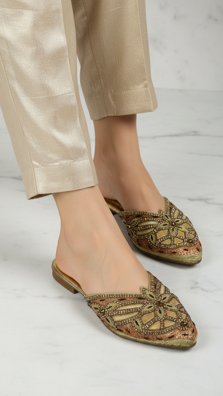 Mule artesanal B&Y com bordados manuais em tons metálicos dourado e bronze, design geométrico floral, salto baixo e acabamento sofisticado, em fundo branco.