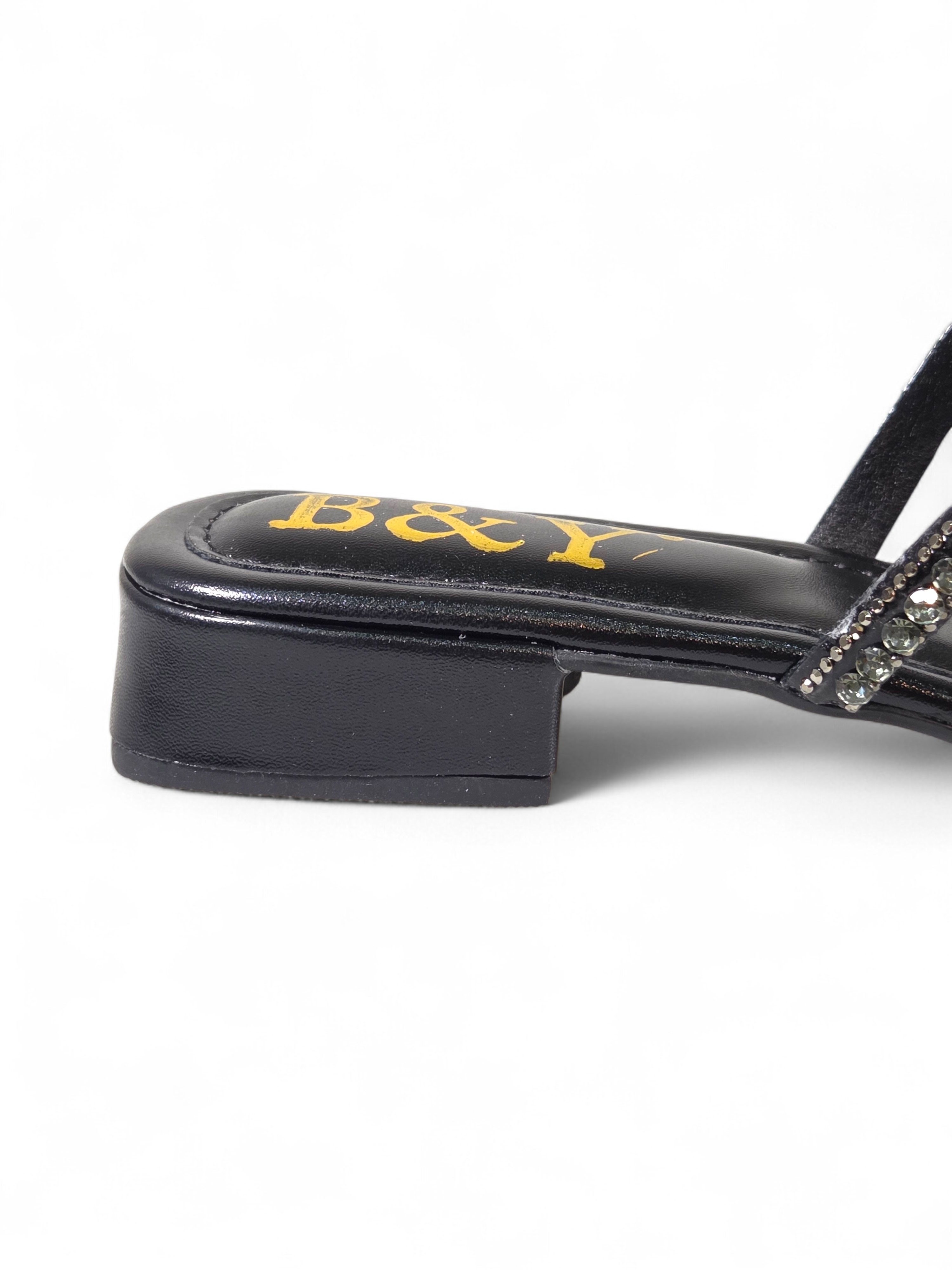 Sandália artesanal B&Y preta com tiras entrelaçadas cravejadas de cristais, salto baixo e acabamento sofisticado, em fundo branco.