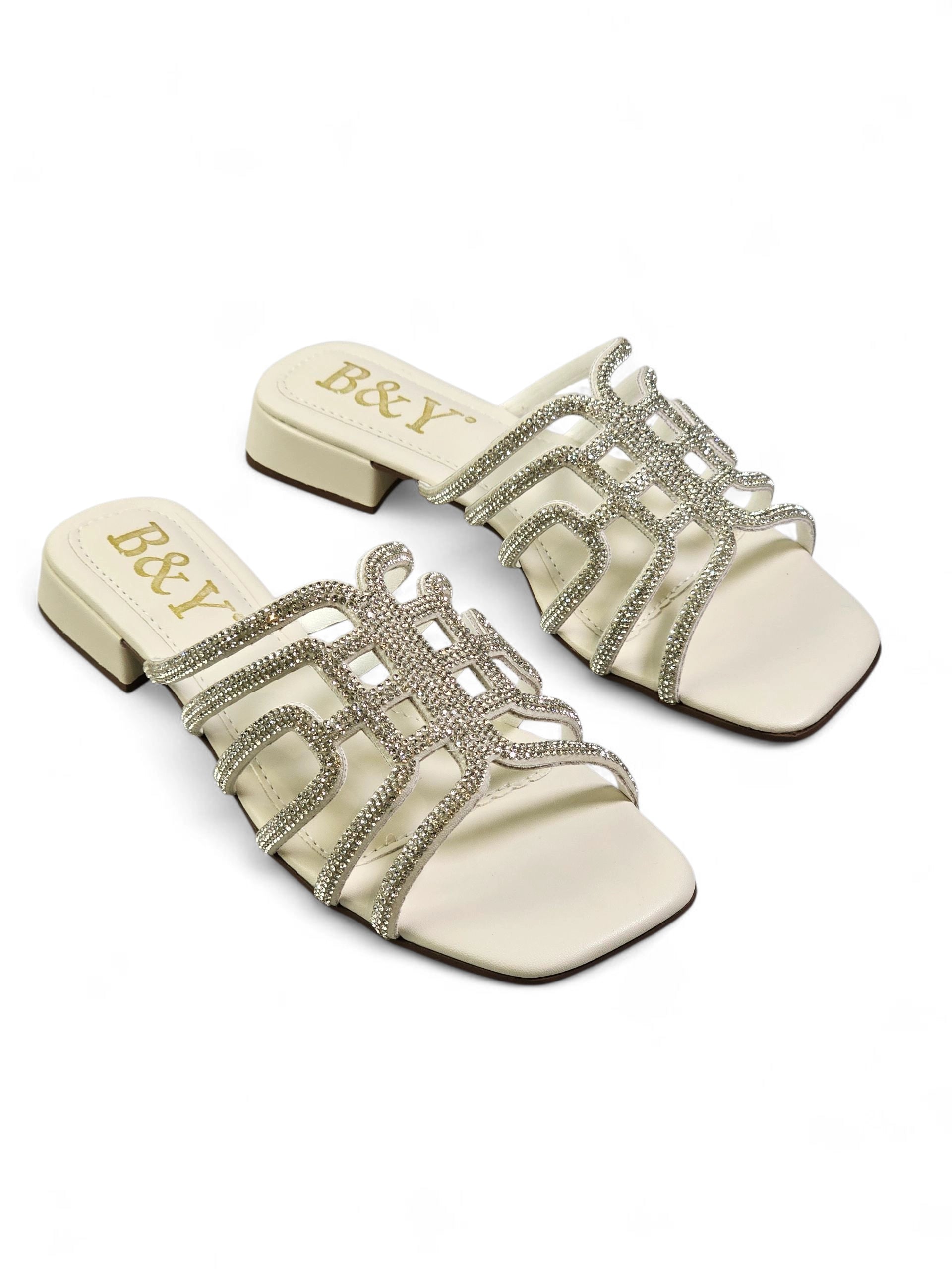 Sandália branca artesanal com tiras entrelaçadas e cristais brilhantes.