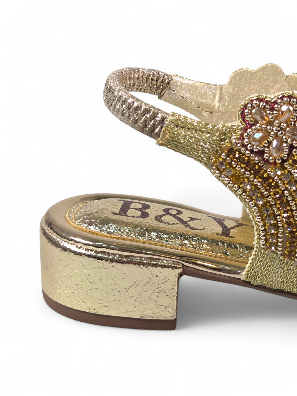 Sandália artesanal B&Y dourada com bordados florais, aplicação de cristais, fechamento no calcanhar e salto baixo, em fundo branco.