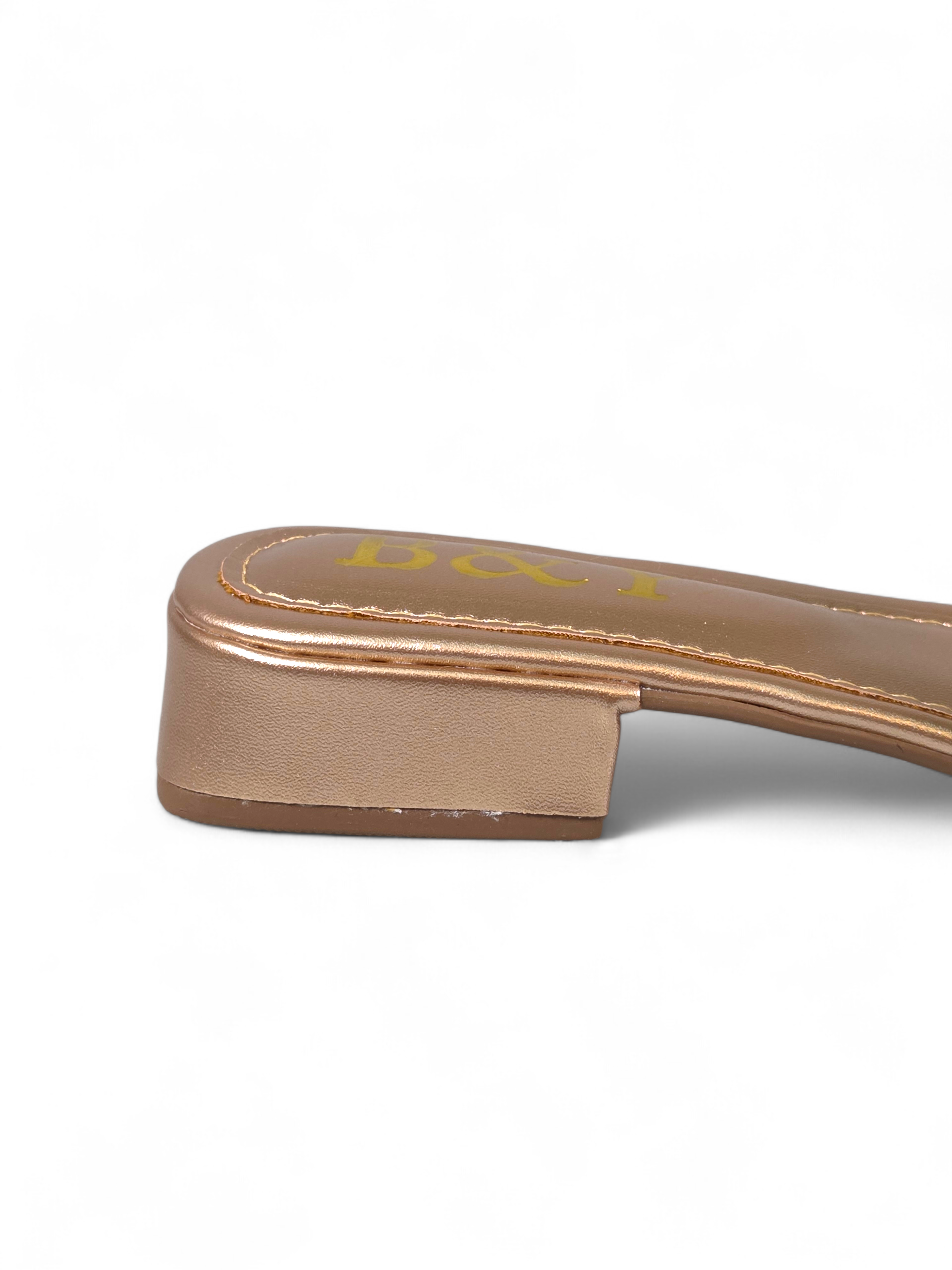 Sandália artesanal B&Y dourada com duas tiras cravejadas de cristais, salto baixo e acabamento metálico, em fundo branco.