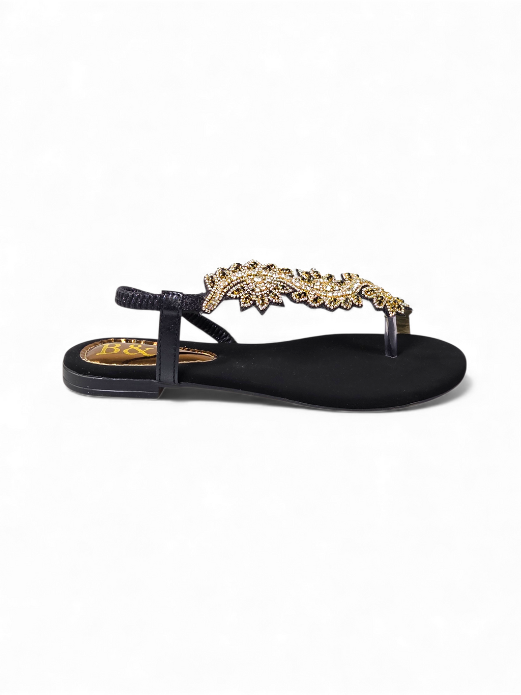 A black sandal with a decorative gold embellishment on the toe area.