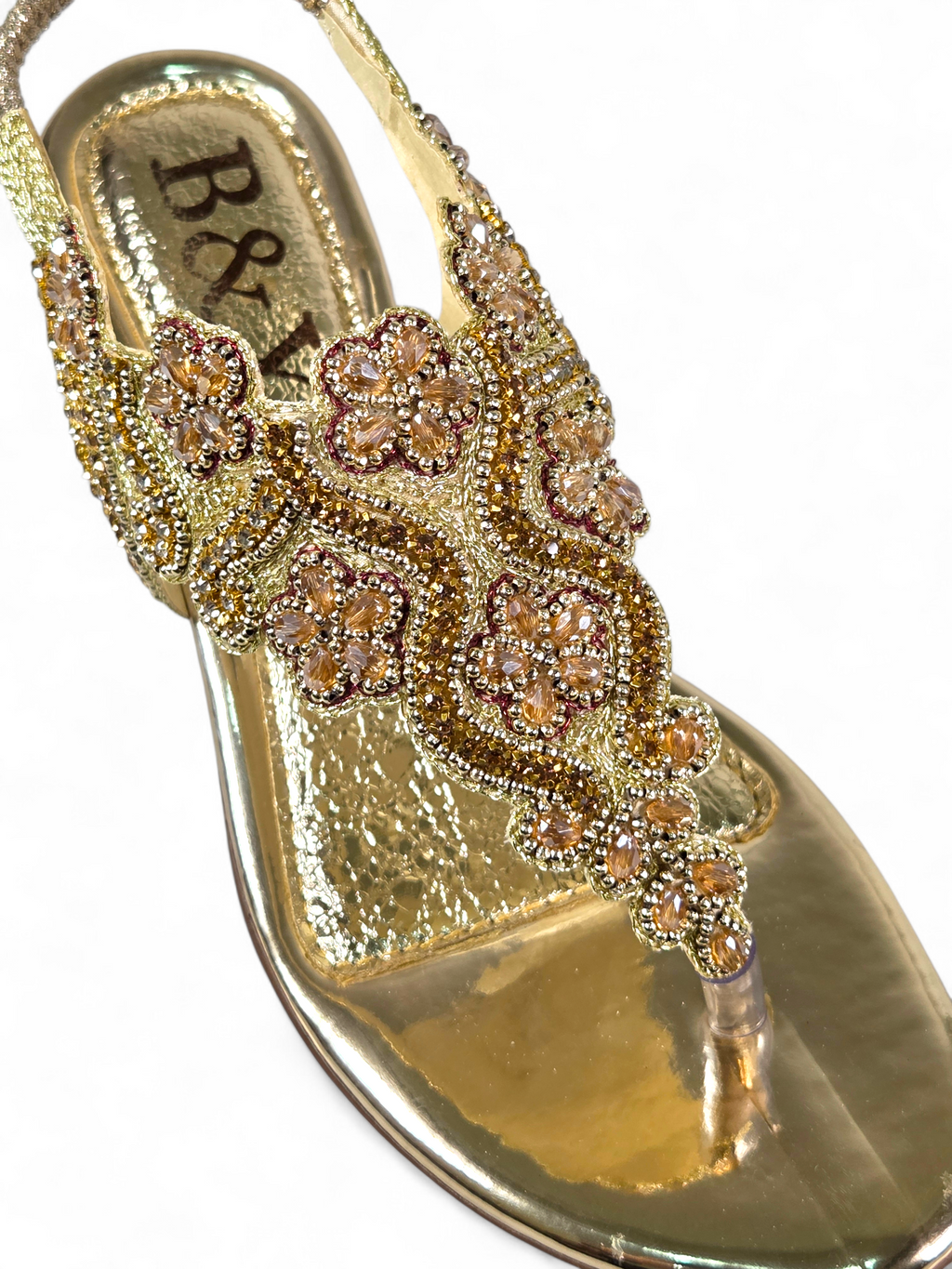 Sandália artesanal B&Y dourada com bordados florais, aplicação de cristais, fechamento no calcanhar e salto baixo, em fundo branco.