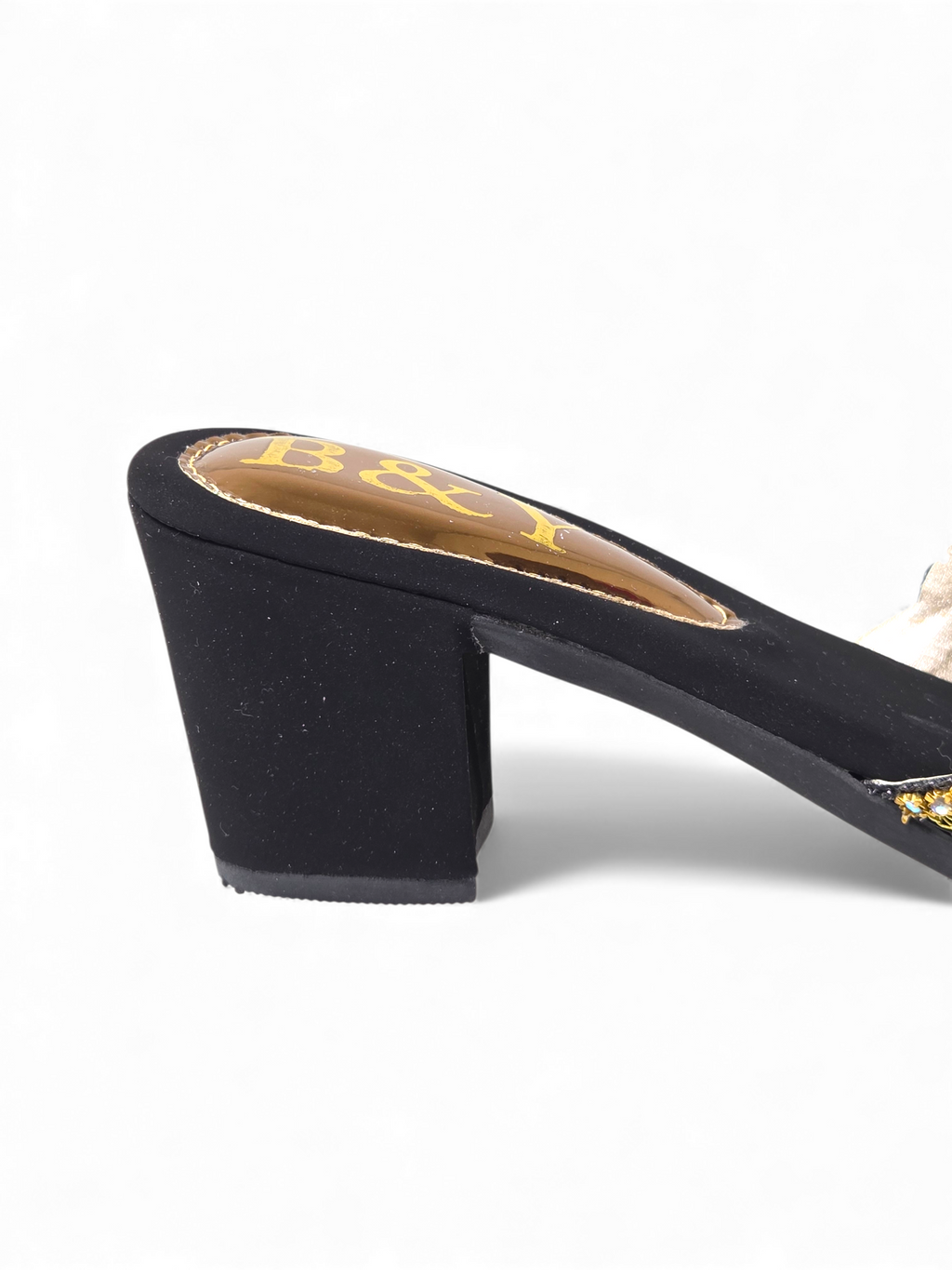 A close-up view of a black high-heeled shoe with a gold heel and the letters "B&I" printed on the heel.