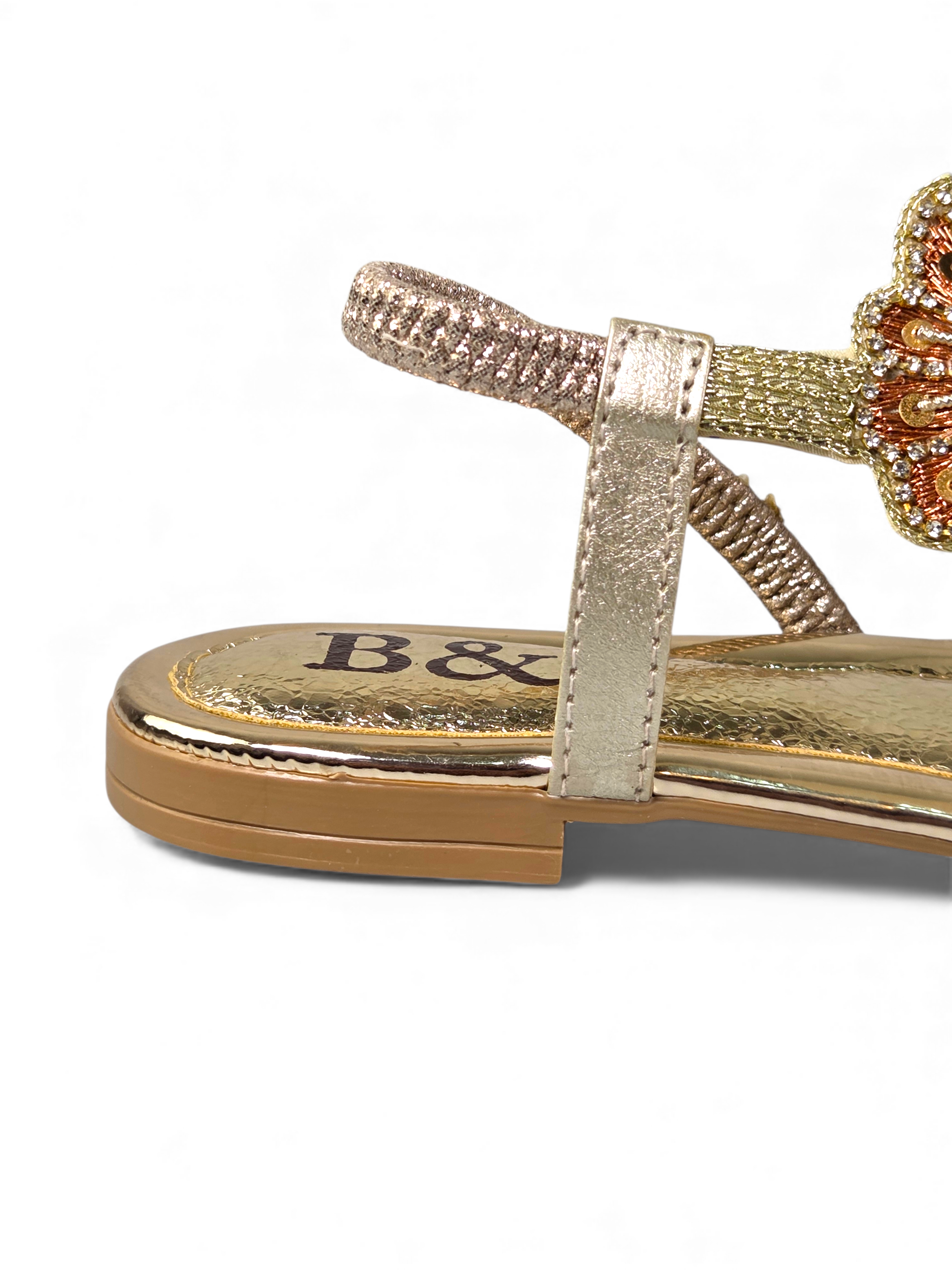 A close-up view of a gold and beige sandal with a floral design on the heel.