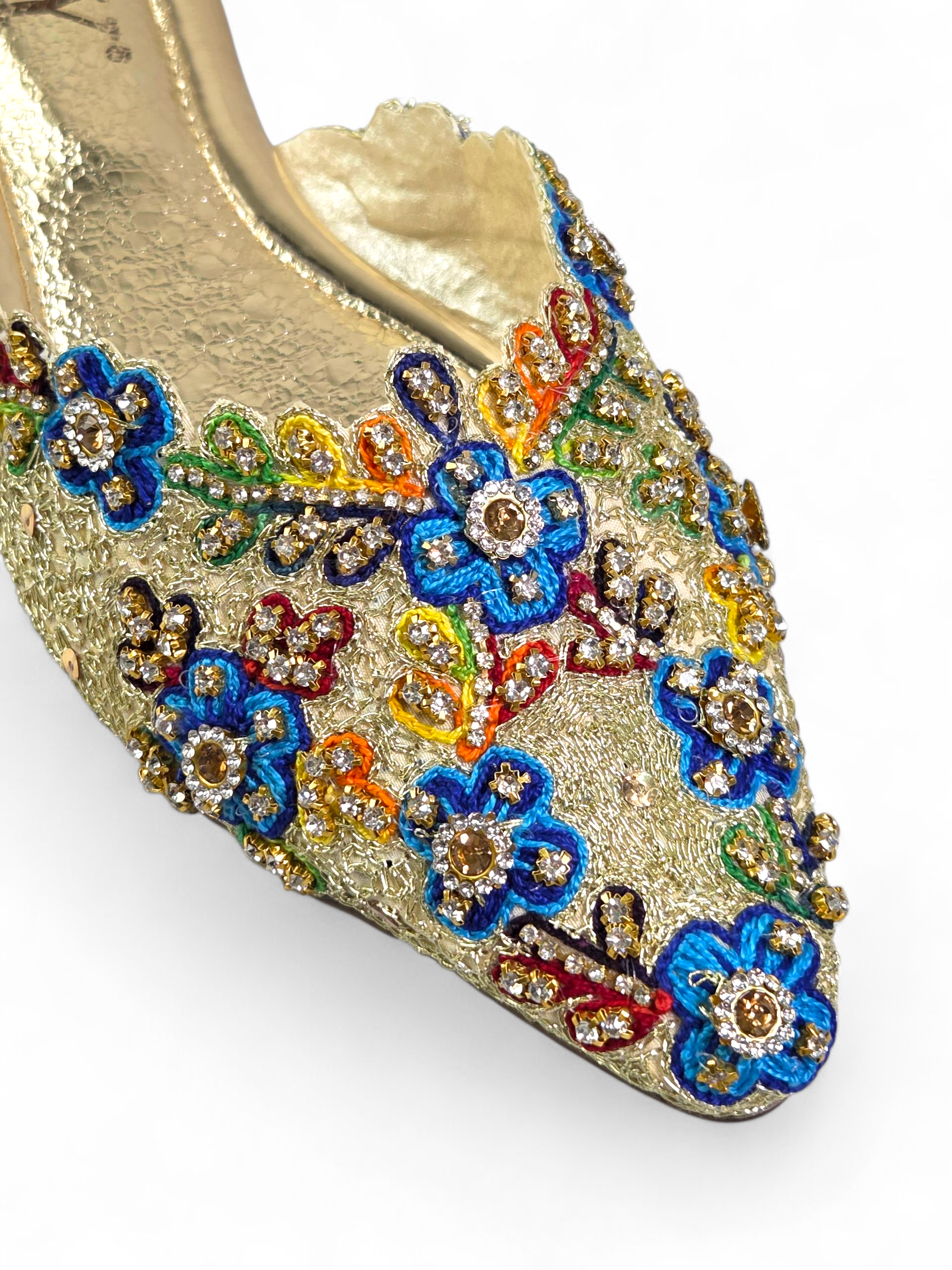Mule artesanal dourada com bordado floral multicolorido feito à mão e pedrarias brilhantes.