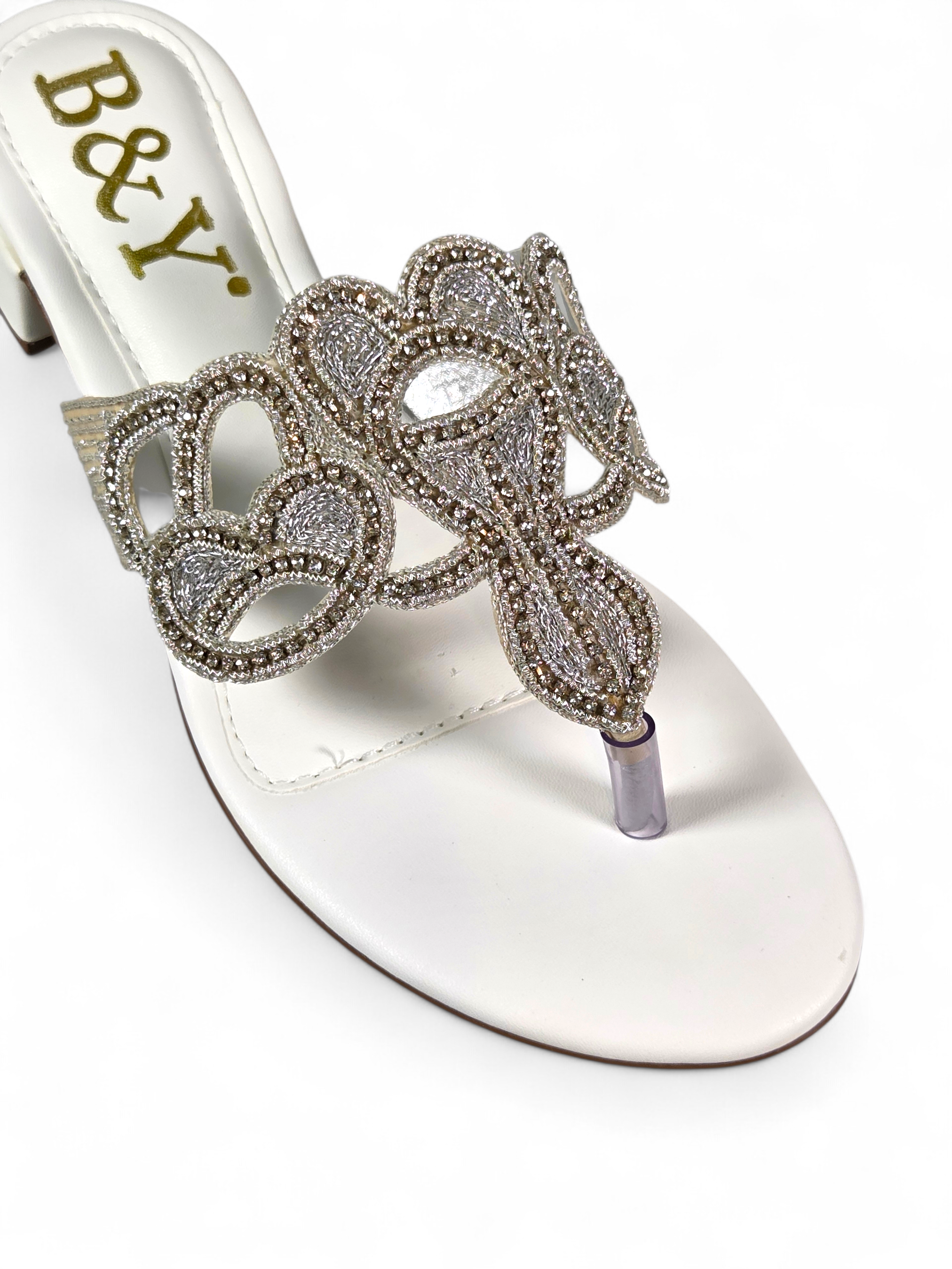 Sandália artesanal B&Y clara com aplicação de cristais, design ornamental, salto baixo e acabamento sofisticado, em fundo branco.