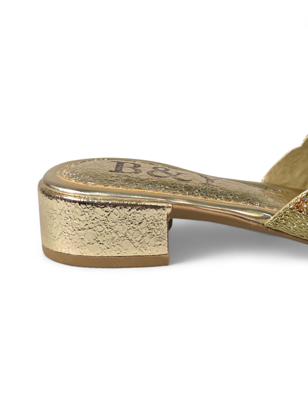 A close-up view of a gold-colored shoe with a textured sole and a small logo on the heel.