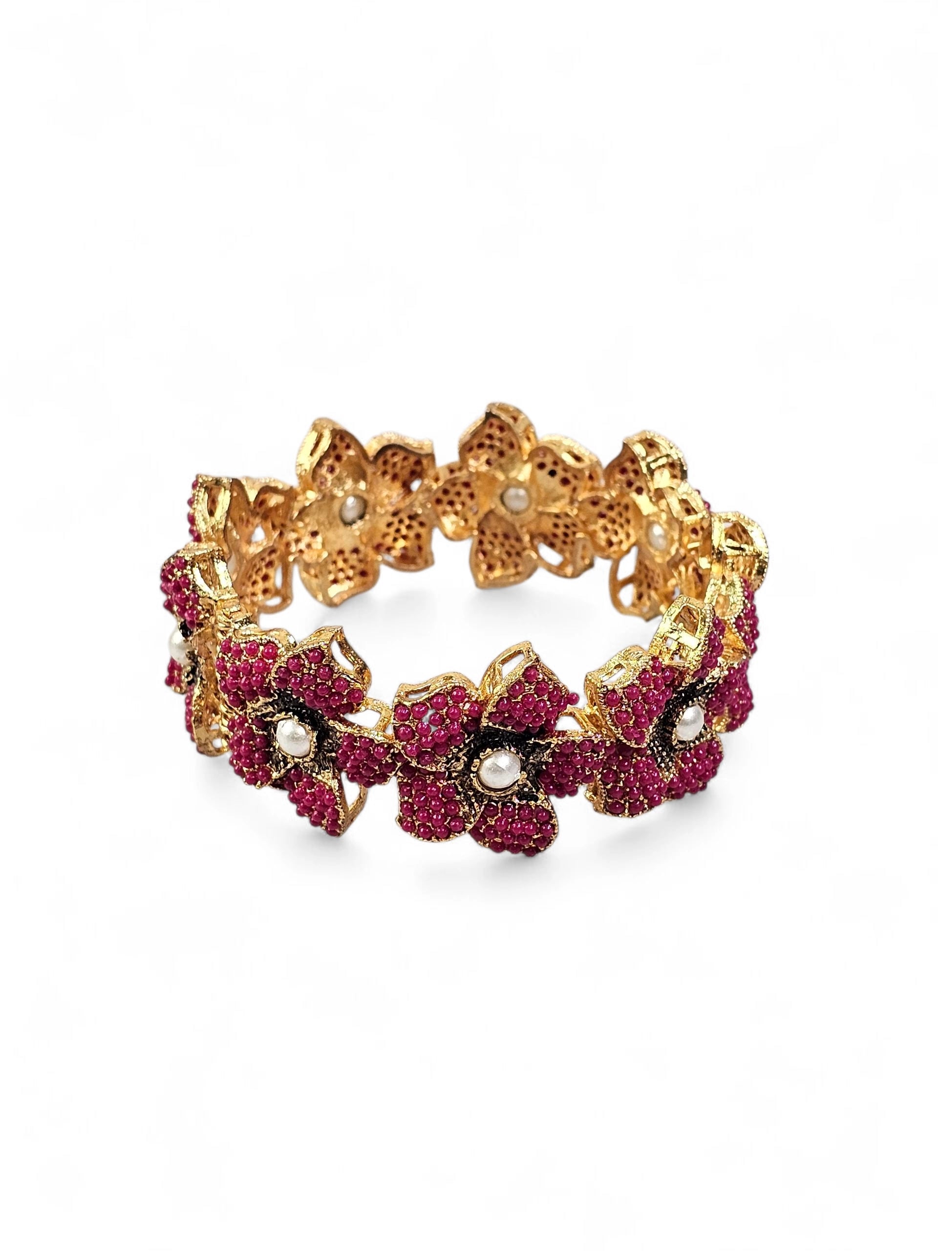 Bracelete floral artesanal B&Y com flores rosa-rubi, detalhes dourados e pérolas centrais.