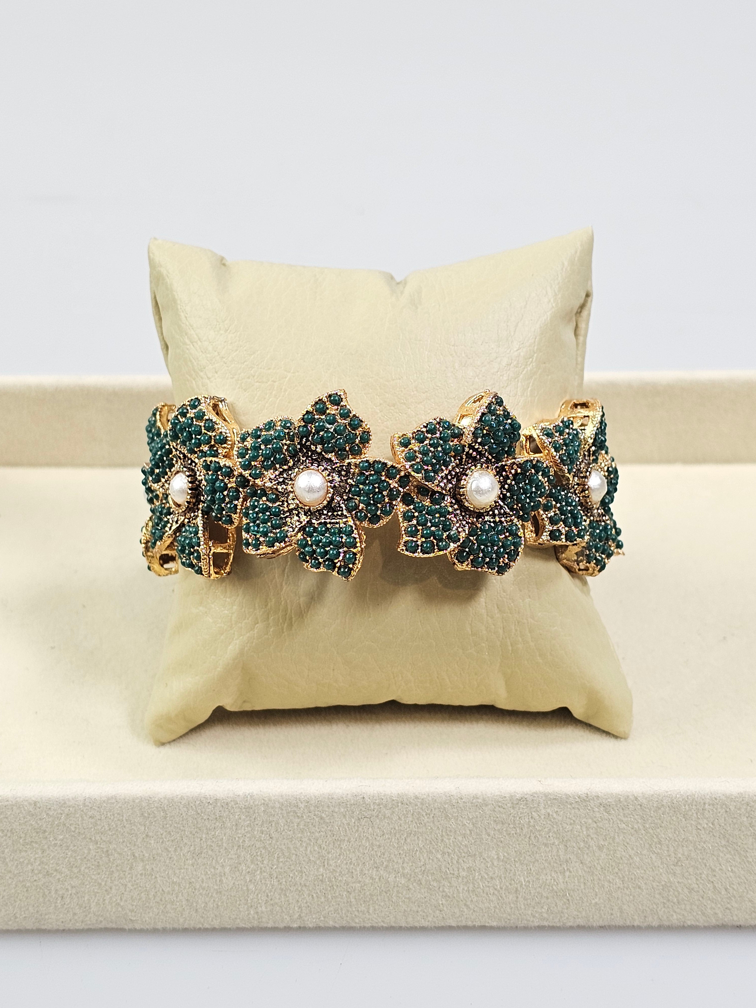 Bracelete floral B&Y com flores verde-esmeralda, detalhes dourados e pérolas no centro.