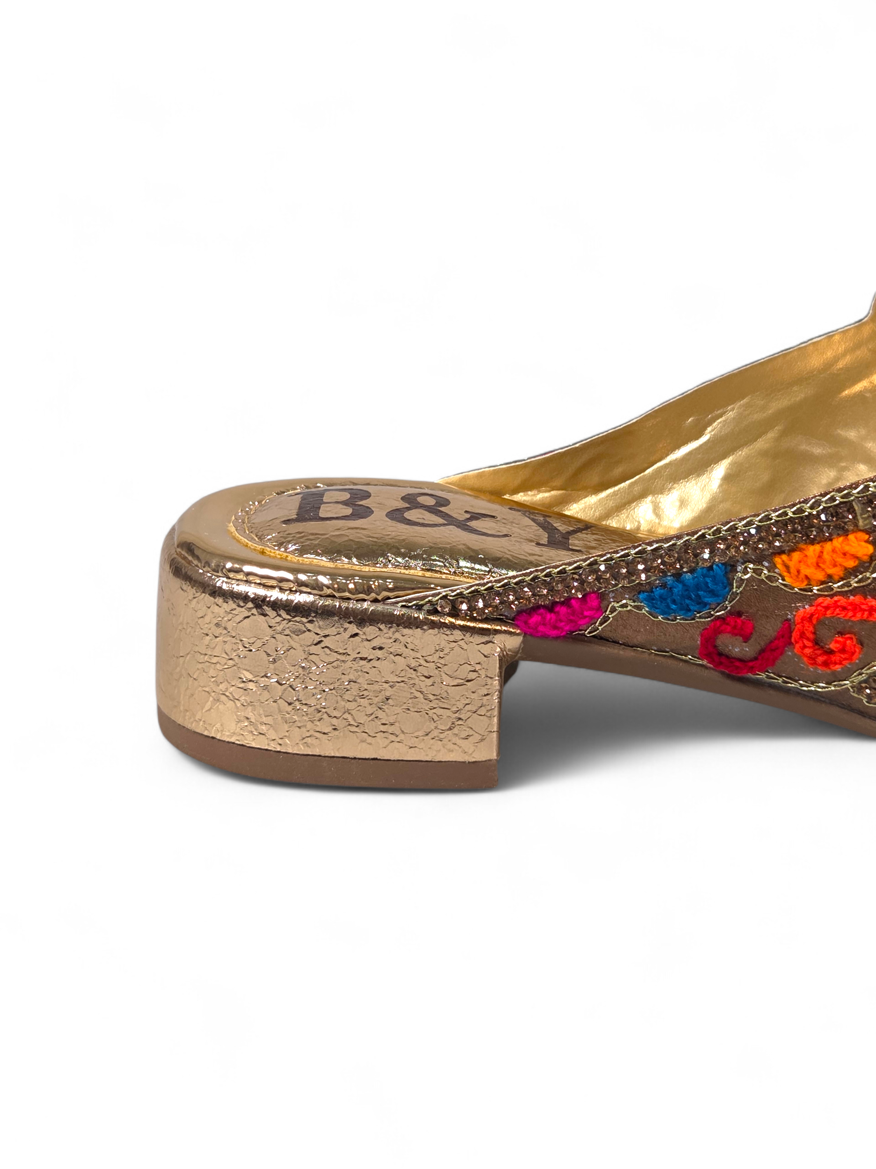 Sandália artesanal B&Y dourada com bordados multicoloridos, aplicação de cristais, salto baixo e acabamento sofisticado, em fundo branco.