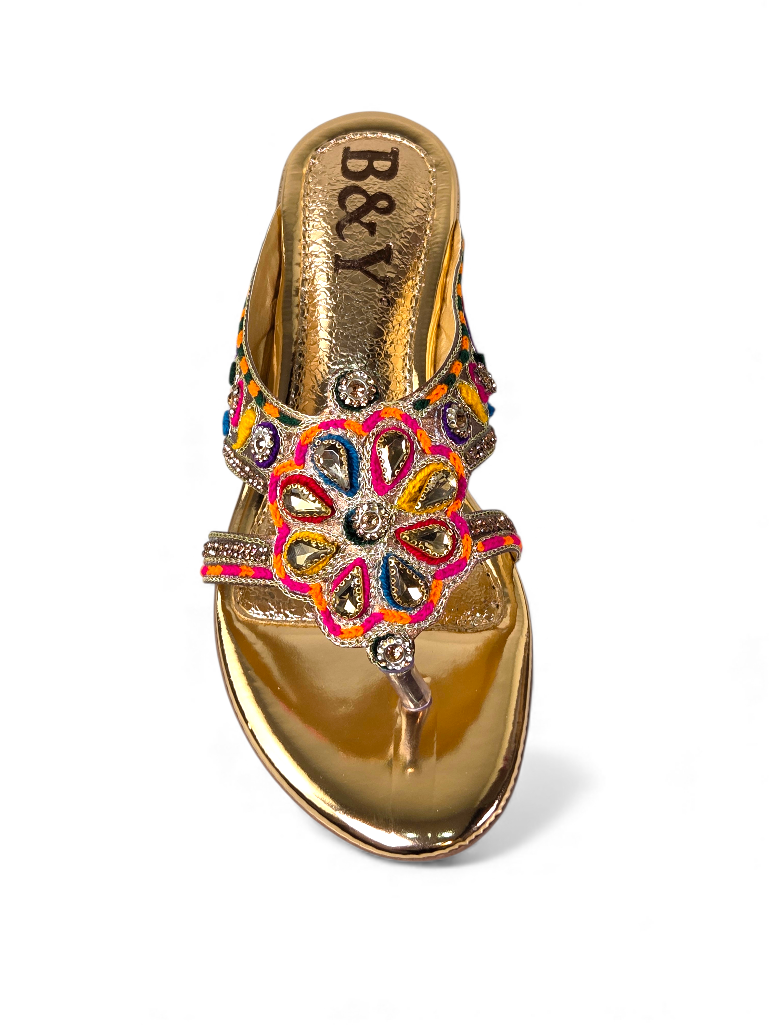 A gold-colored sandal with a floral design and embellishments.