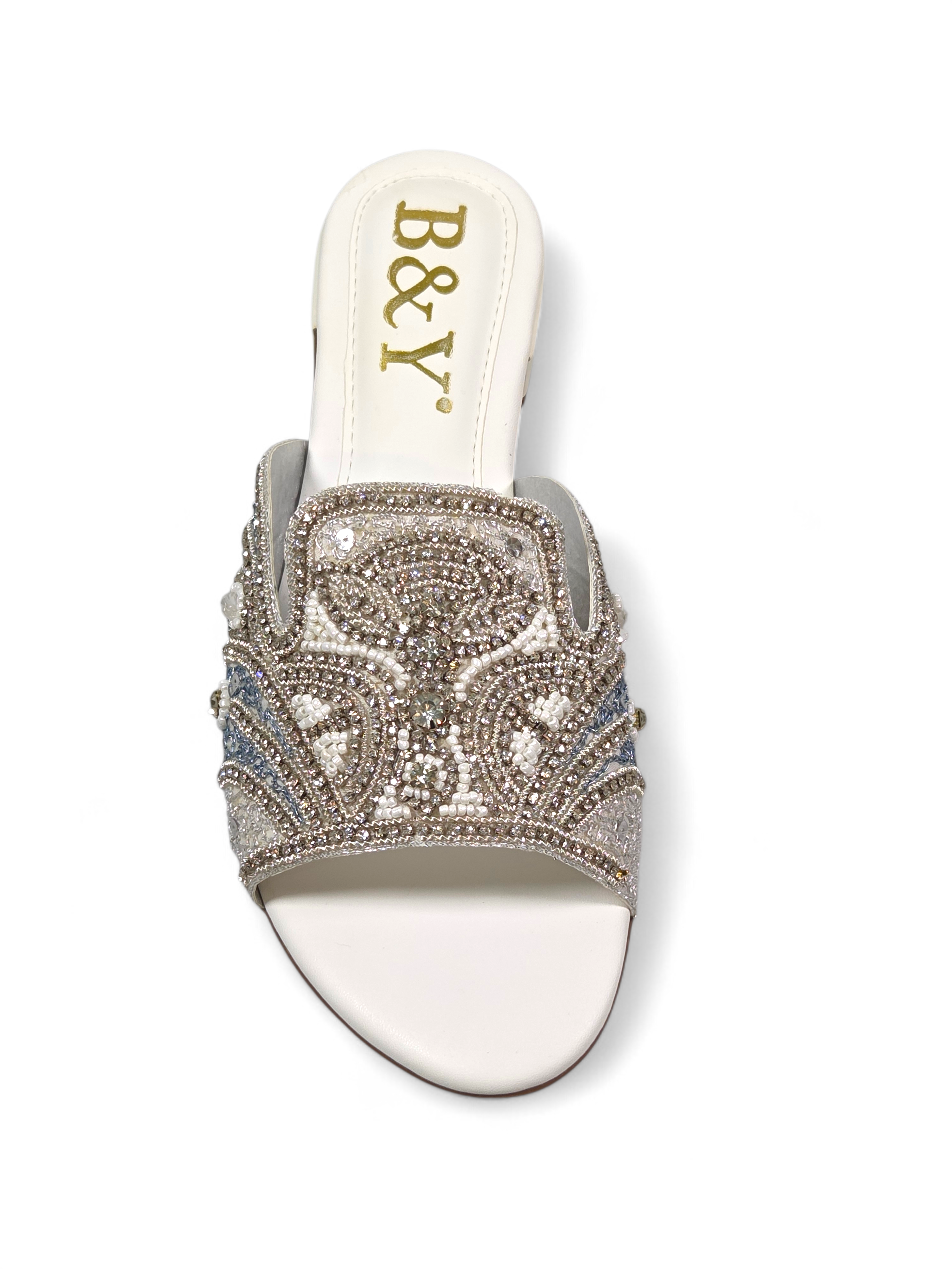 Sandália artesanal B&Y em tom creme com bordado manual em pedrarias douradas, cristais delicados e design floral orgânico, salto baixo e acabamento sofisticado.