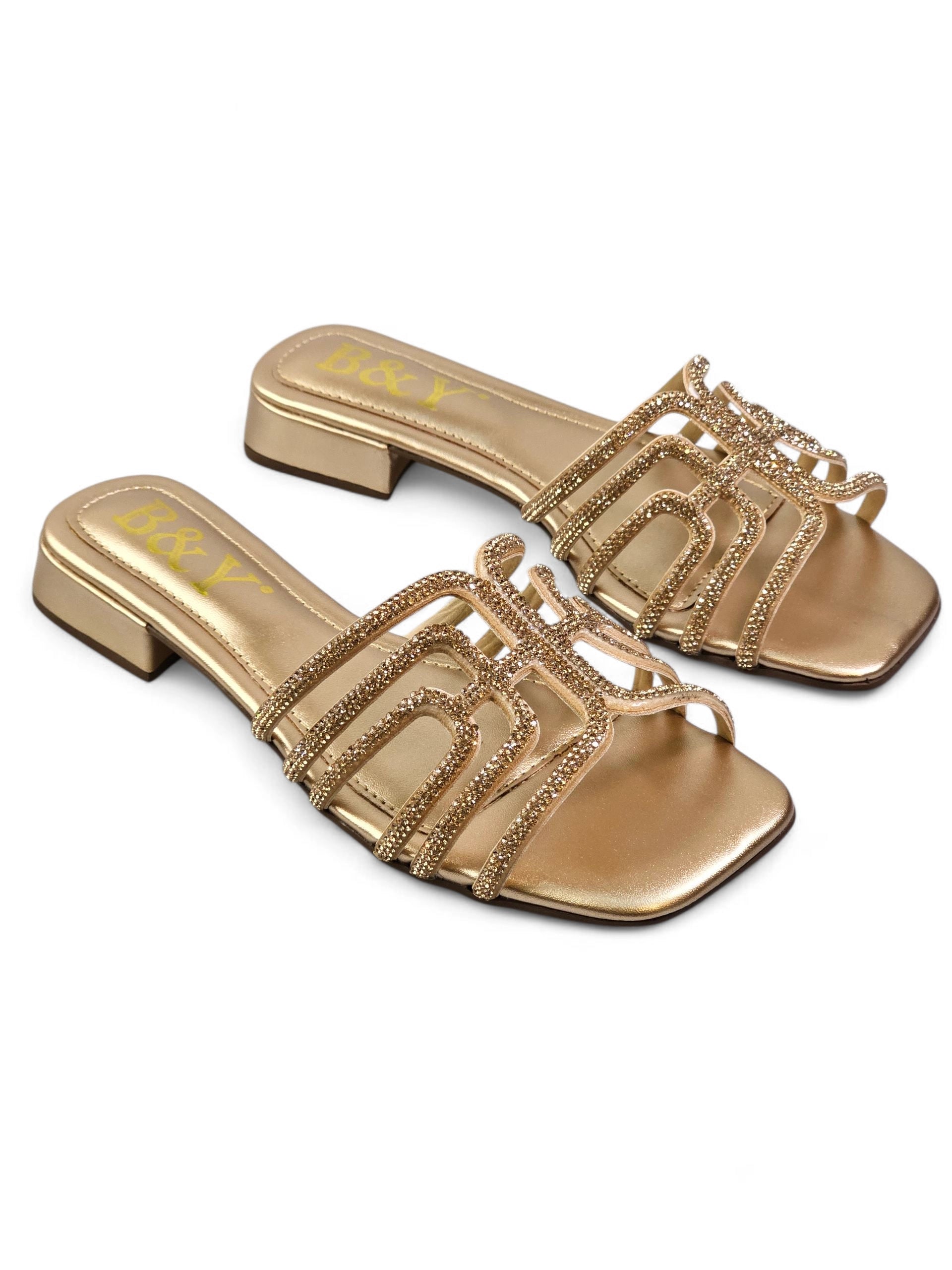 Sandália dourada artesanal com tiras entrelaçadas e cristais cintilantes.