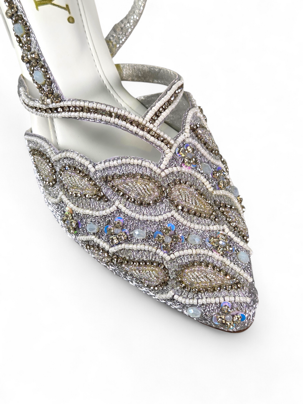Mule artesanal B&Y com bordados delicados, aplicação de cristais em tons prateados, salto baixo e tira no calcanhar, em fundo branco.