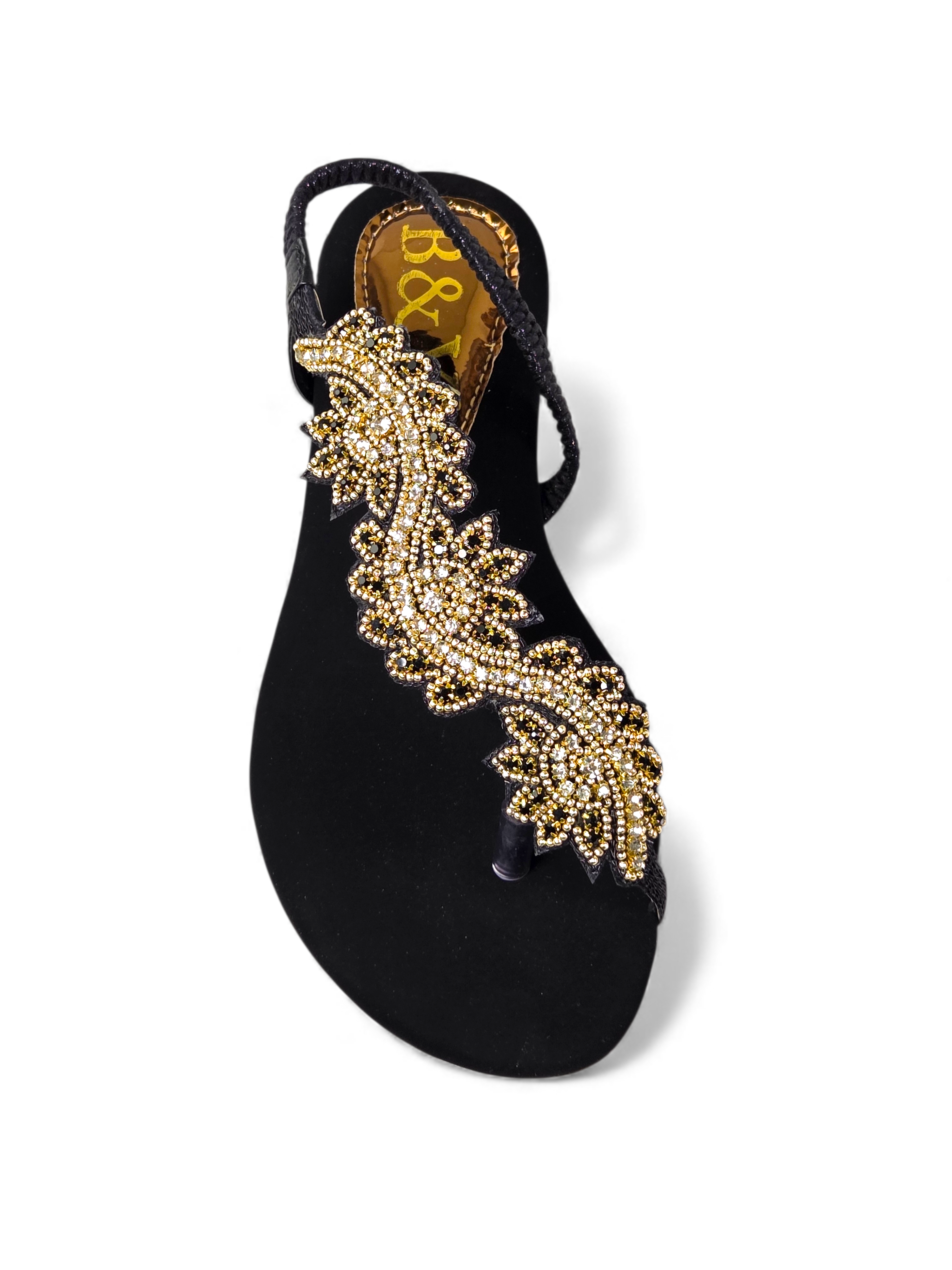A black sandal with a decorative gold leaf design on the toe area.