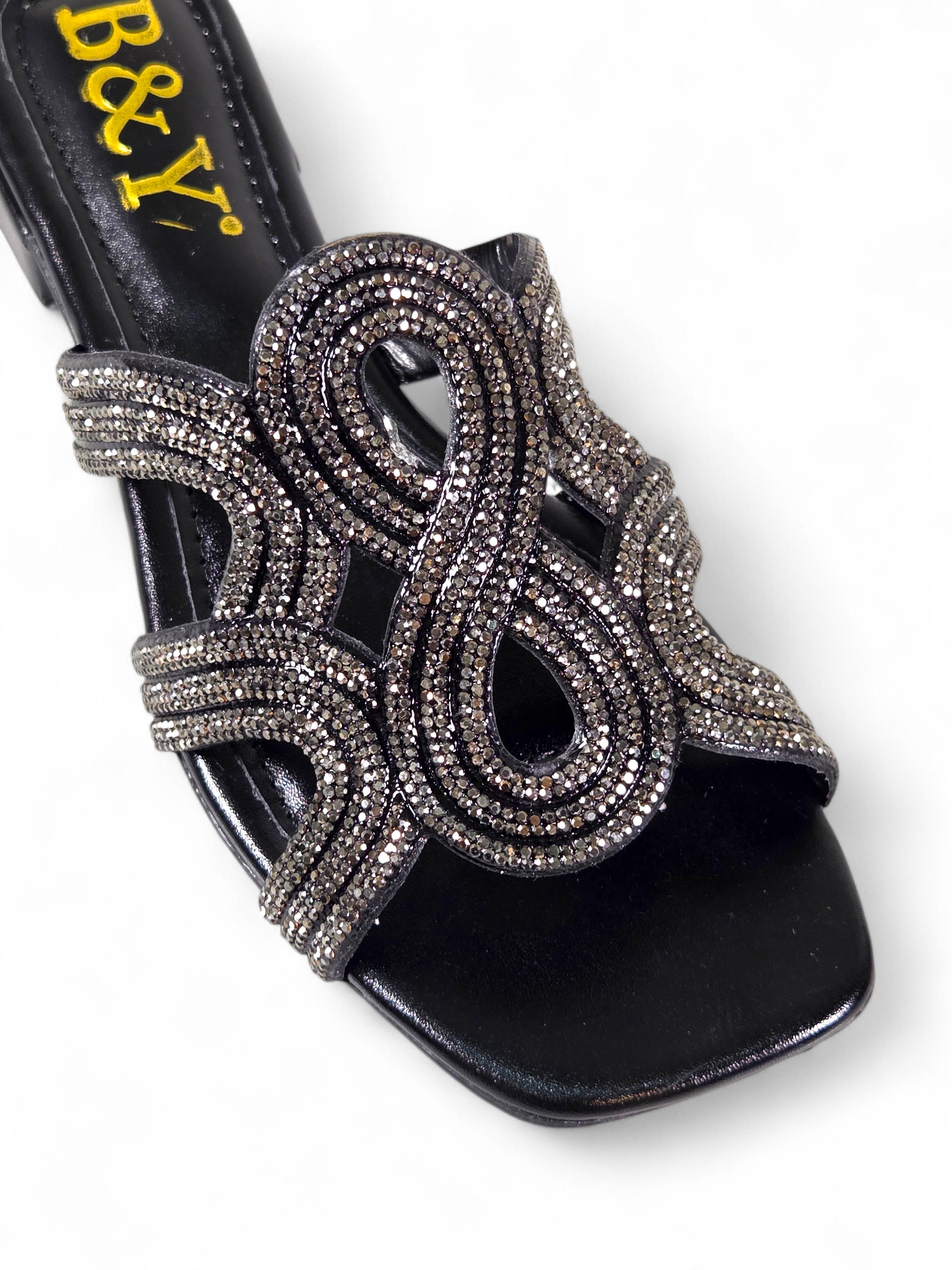 Sandália artesanal B&Y preta com tiras ornamentais cravejadas de cristais, salto baixo e acabamento sofisticado, em fundo branco.