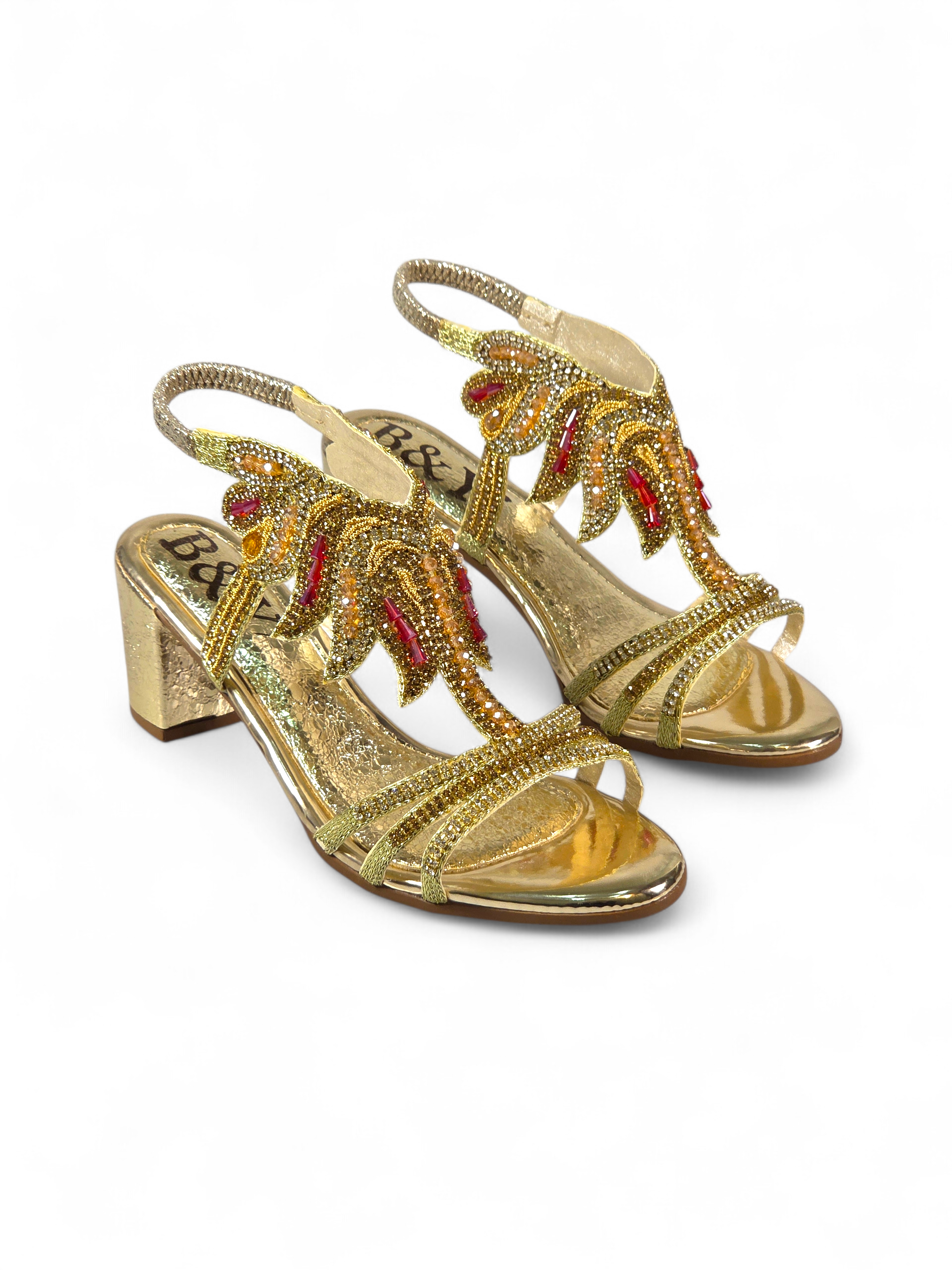 Sandália artesanal B&Y dourada com bordados manuais, cristais e pedrarias em tons de dourado e vermelho, salto médio e acabamento sofisticado, em fundo branco.