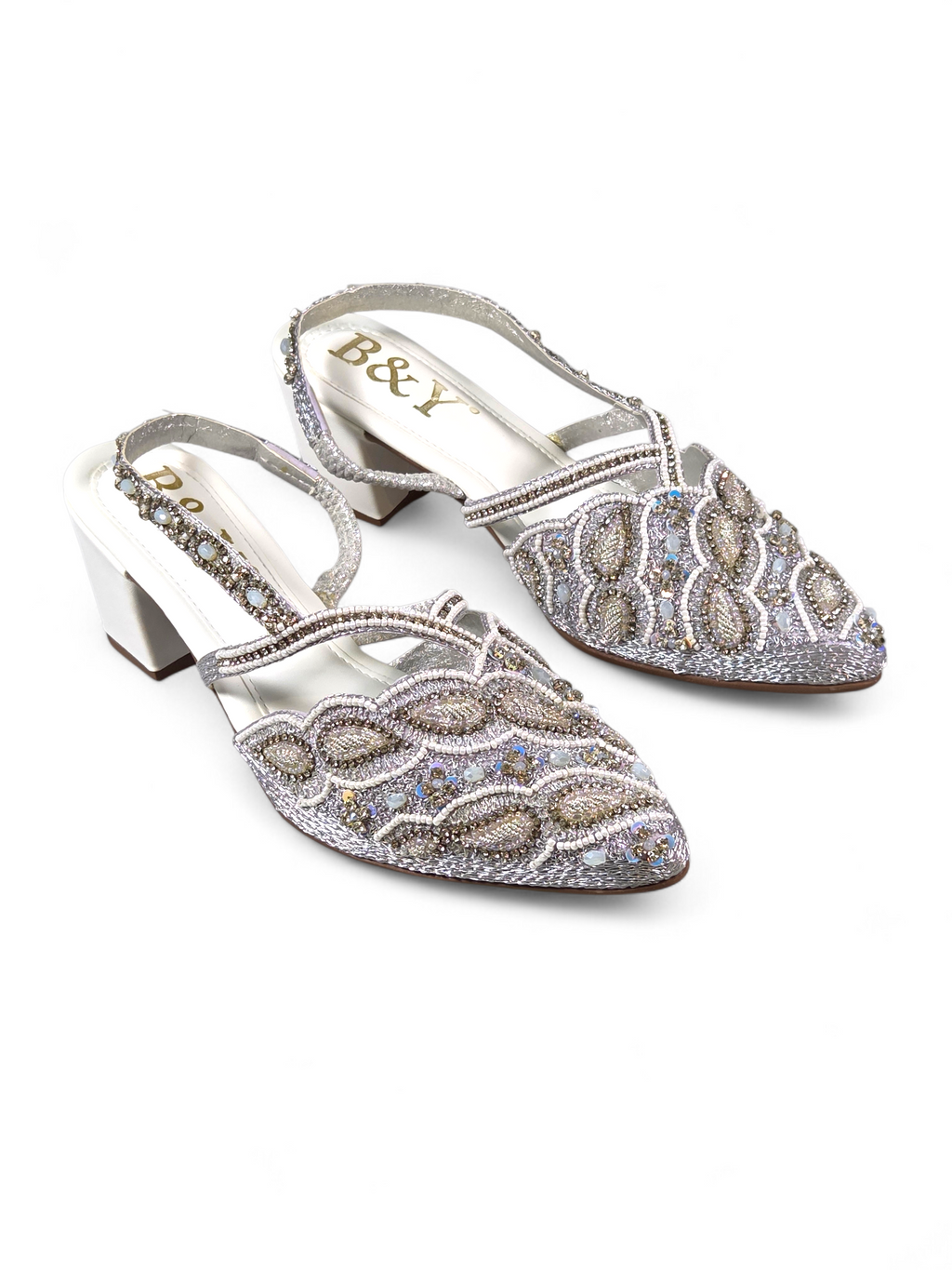 Mule artesanal B&Y com bordados delicados, aplicação de cristais em tons prateados, salto baixo e tira no calcanhar, em fundo branco.