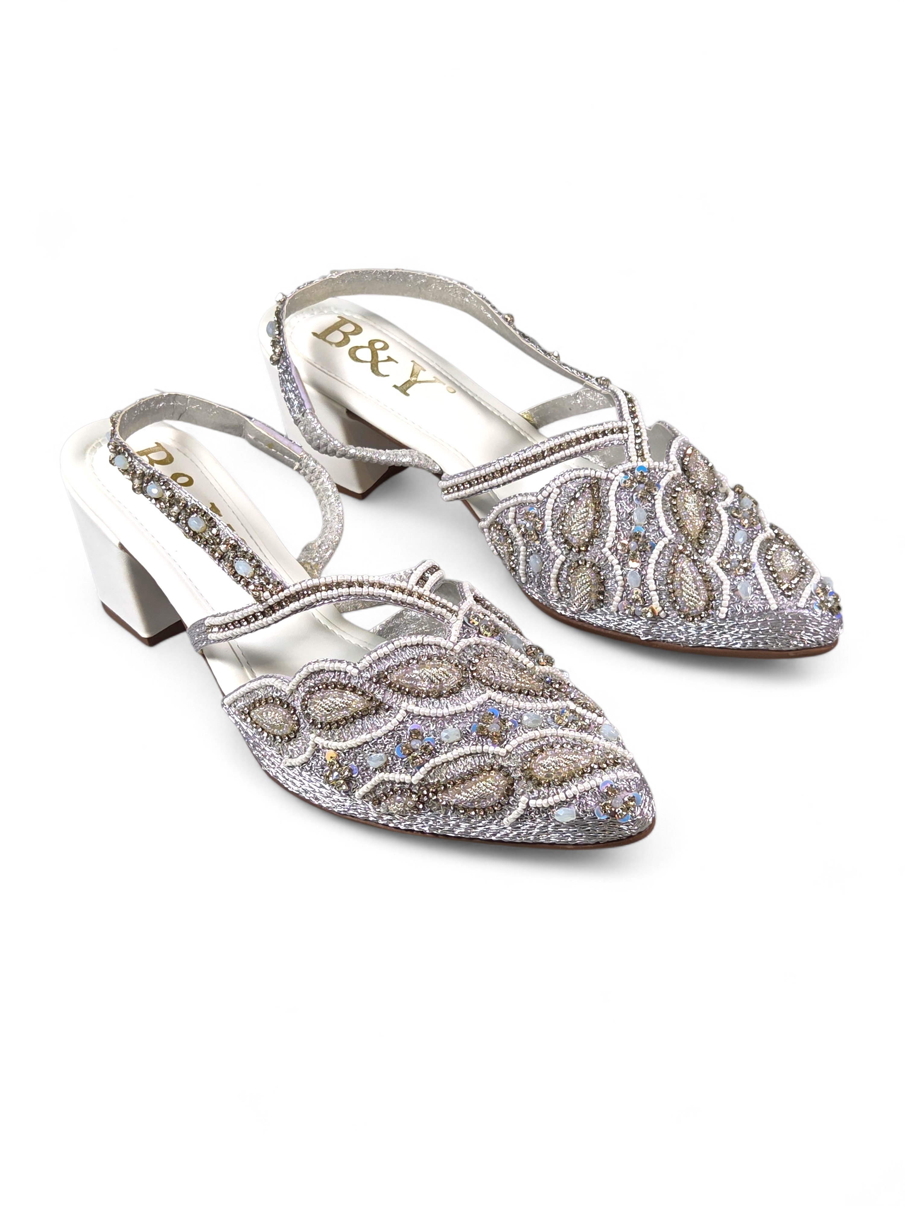 Mule artesanal B&Y com bordados delicados, aplicação de cristais em tons prateados, salto baixo e tira no calcanhar, em fundo branco.