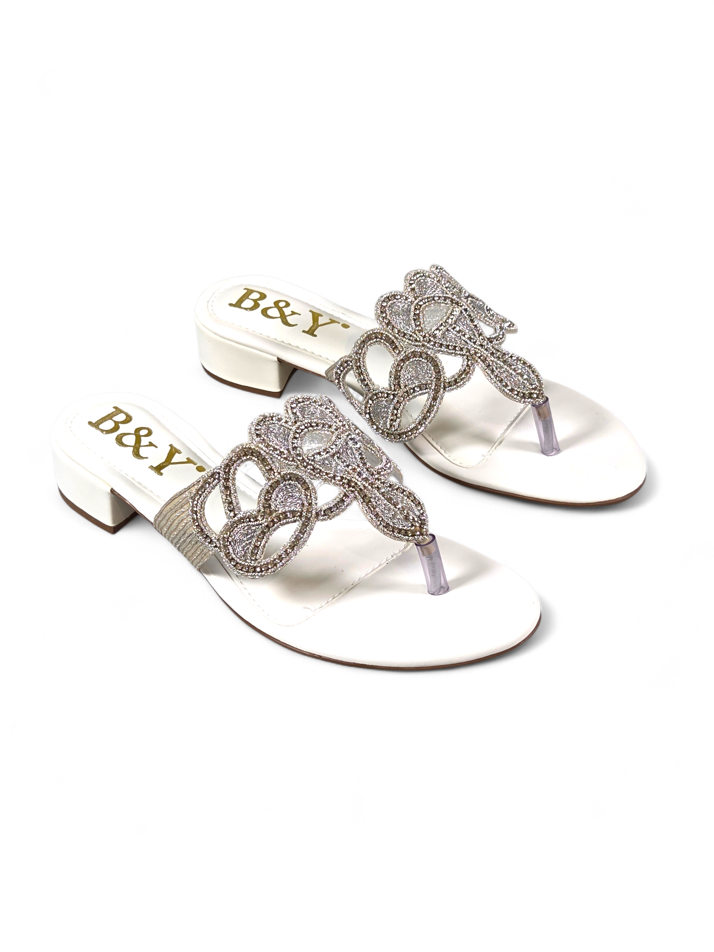 Sandália artesanal B&Y clara com aplicação de cristais, design ornamental, salto baixo e acabamento sofisticado, em fundo branco.