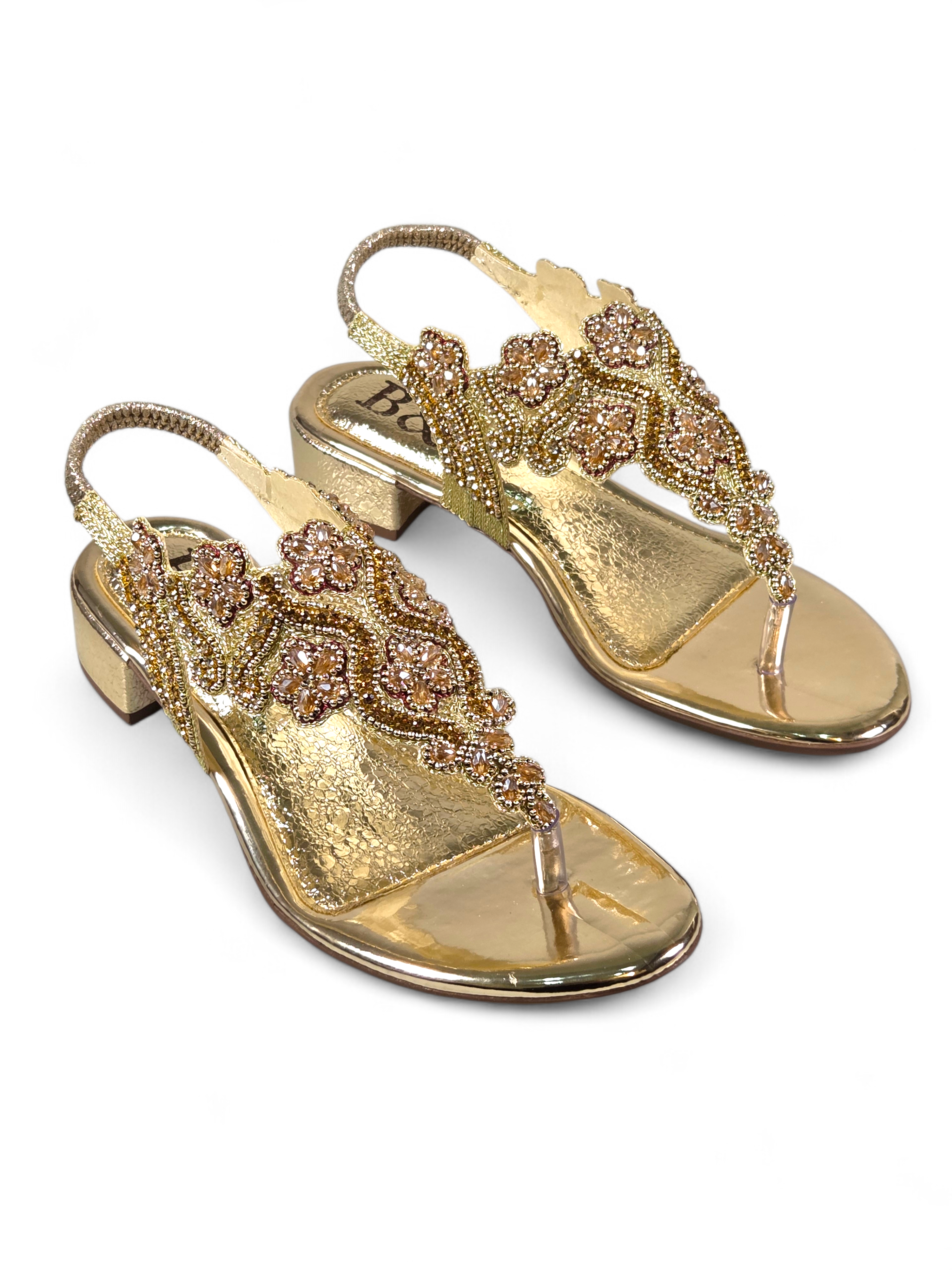 Sandália artesanal B&Y dourada com bordados florais, aplicação de cristais, fechamento no calcanhar e salto baixo, em fundo branco.
