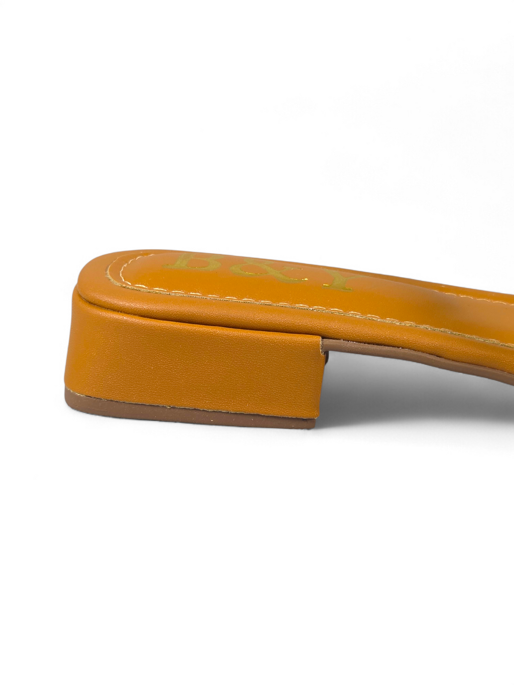 Sandália artesanal B&Y em tom quente com duas tiras cravejadas de cristais, salto baixo e acabamento sofisticado, em fundo branco.