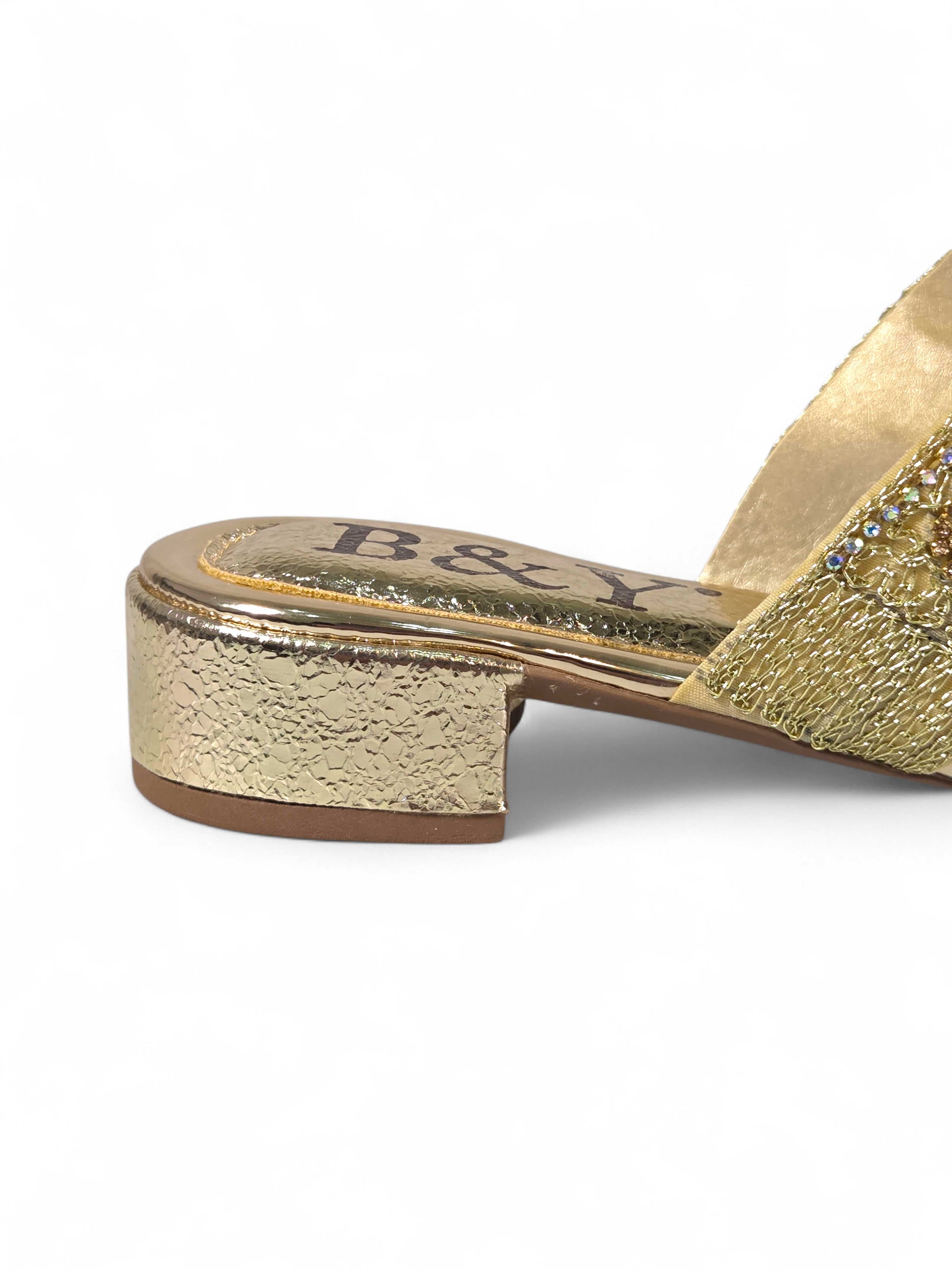 Sandália artesanal B&Y dourada com tiras bordadas, aplicação de cristais e salto baixo, fotografada em fundo branco.