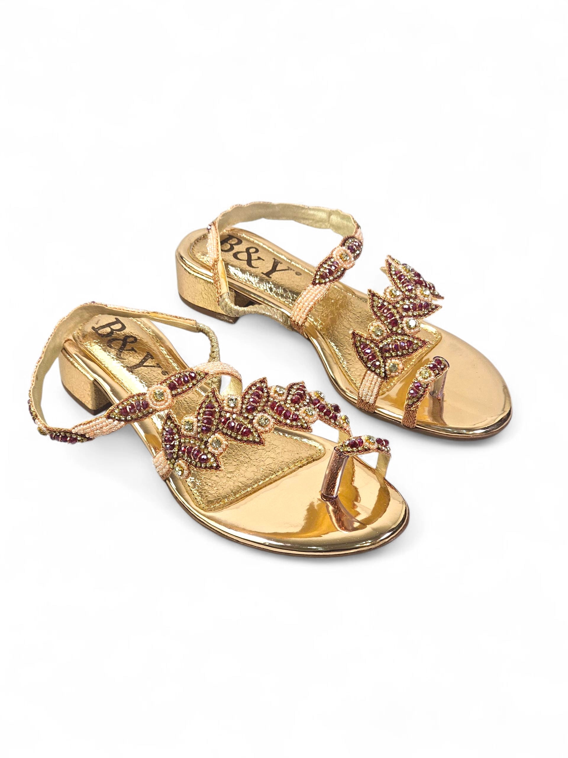 Sandália artesanal dourada com pedrarias rubi e pérolas, design em folhas, feita à mão com miçangas e brilho sofisticado.