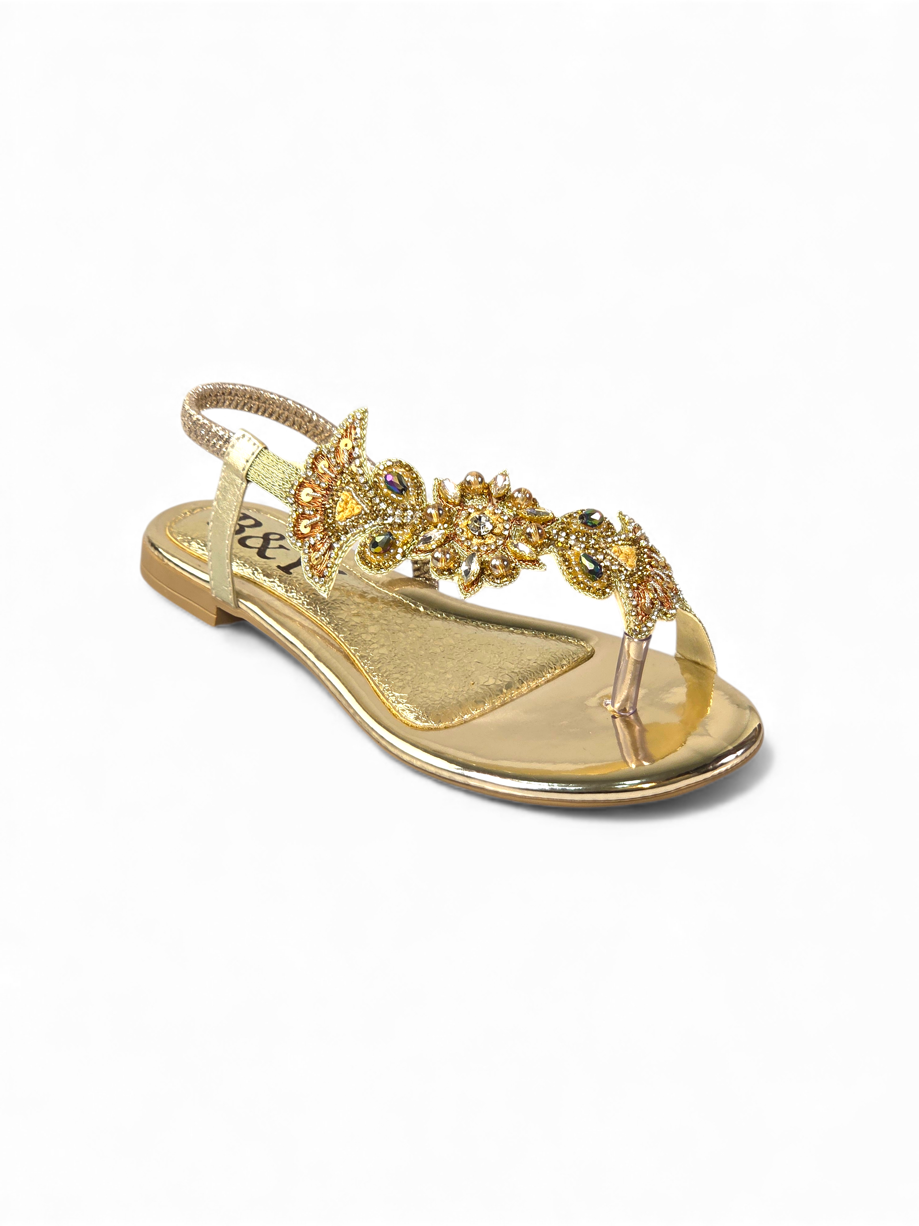 A gold-colored sandal with a decorative floral embellishment on the toe area.