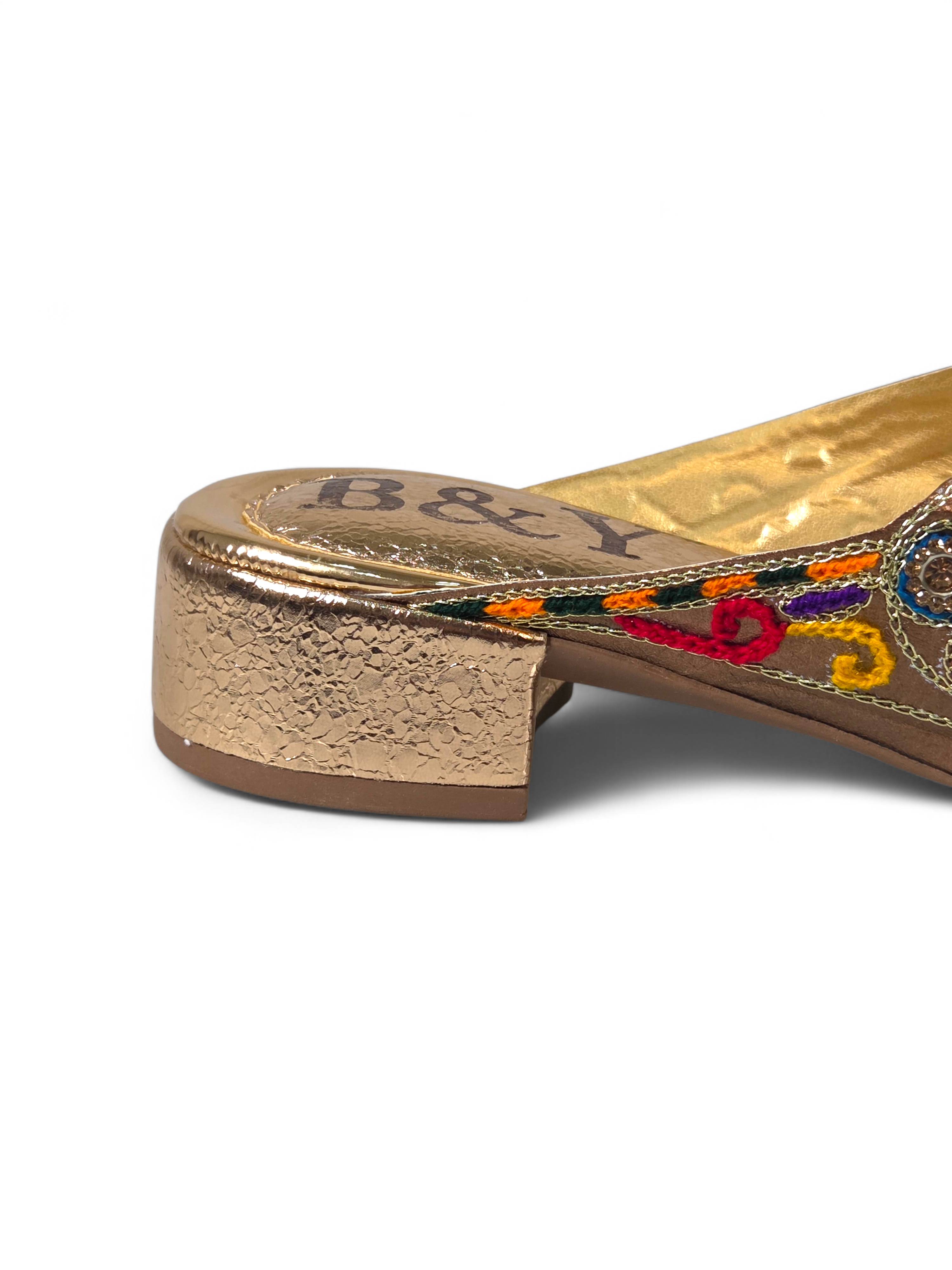 Sandália artesanal B&Y dourada com bordados multicoloridos, aplicação de cristais, salto baixo e acabamento sofisticado, em fundo branco.