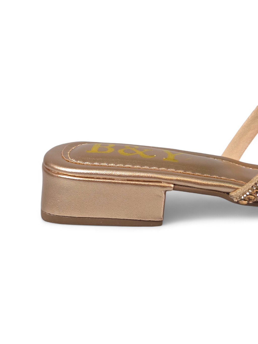 Sandália artesanal B&Y dourada com tiras ornamentais cravejadas de cristais, salto baixo e acabamento metálico, em fundo branco.