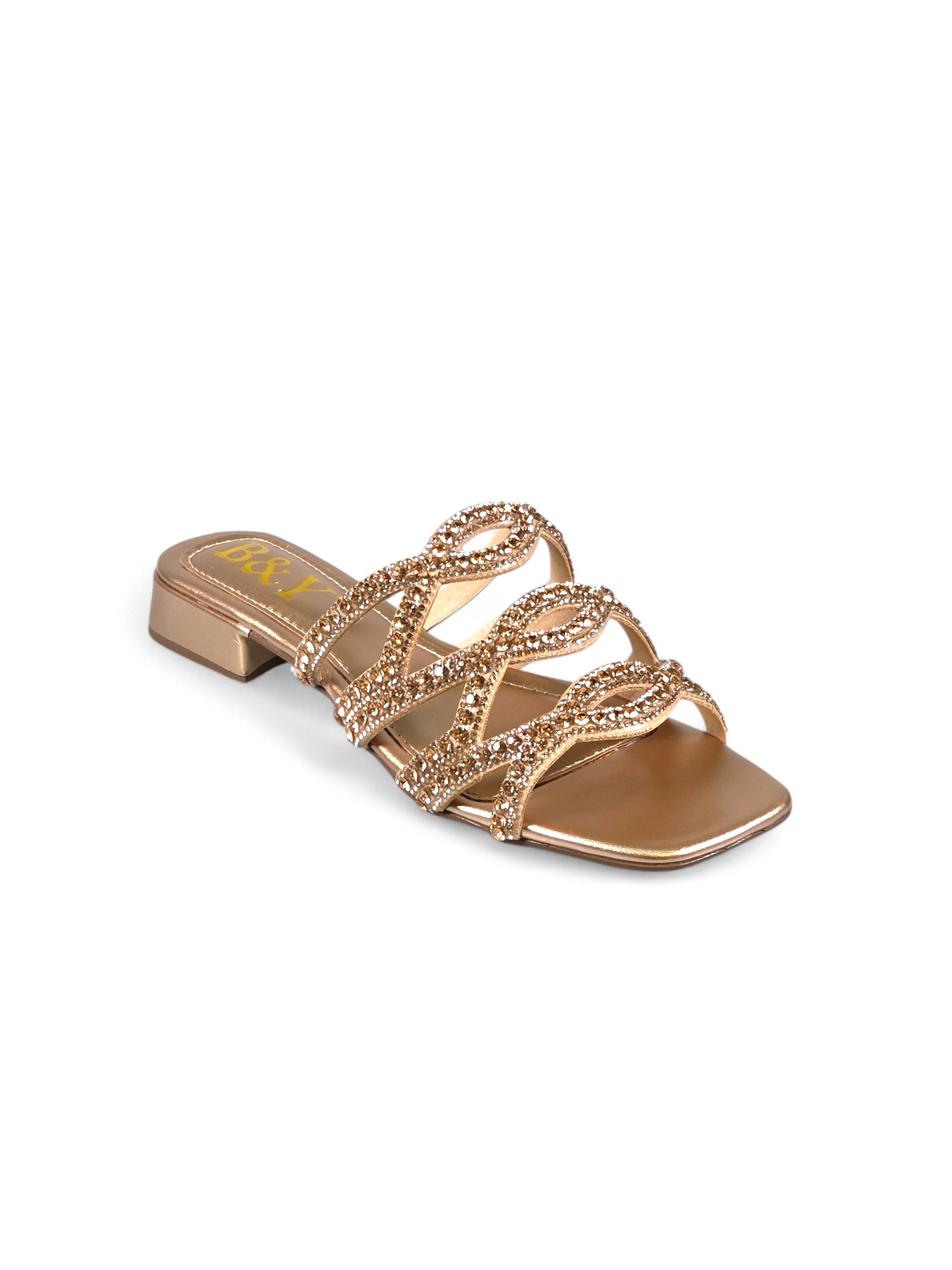 Sandália artesanal B&Y dourada com tiras ornamentais cravejadas de cristais, salto baixo e acabamento metálico, em fundo branco.