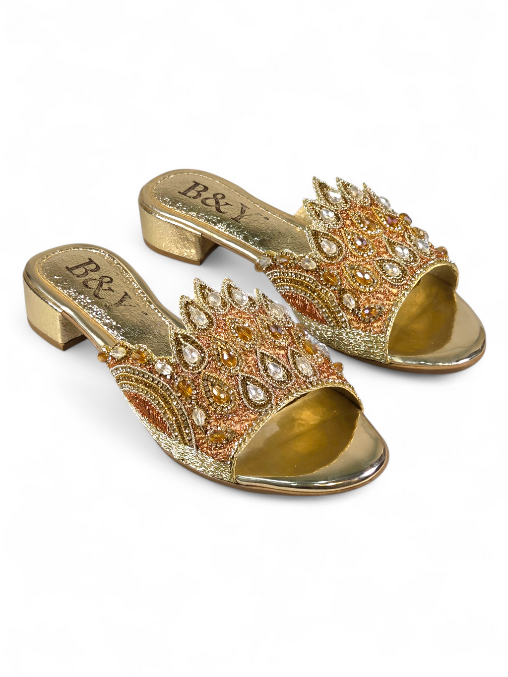 A pair of gold and beige embellished sandals with intricate designs and rhinestones.