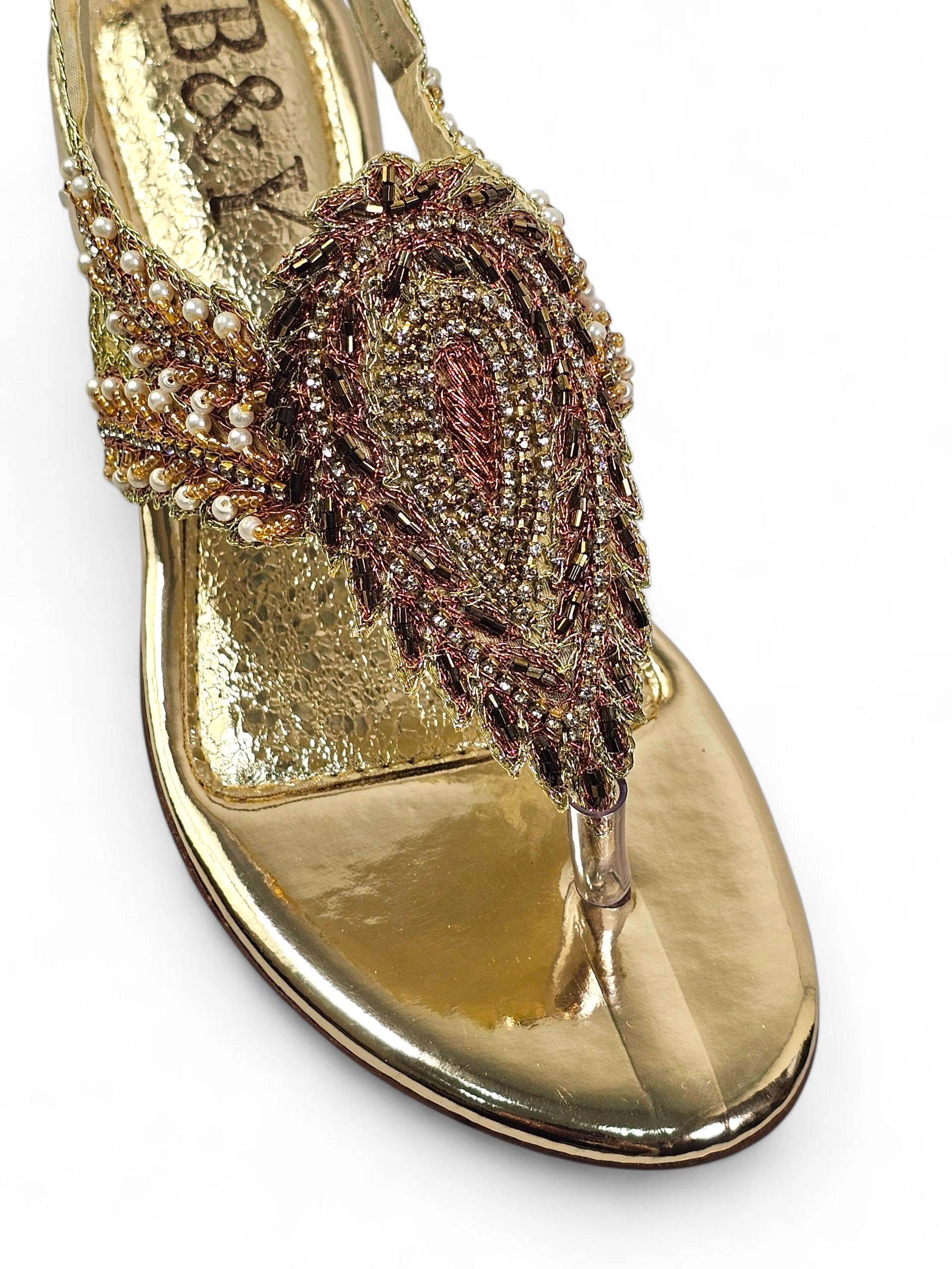 Sandália artesanal feminina dourada feita à mão com bordado de pedrarias e fios metálicos.