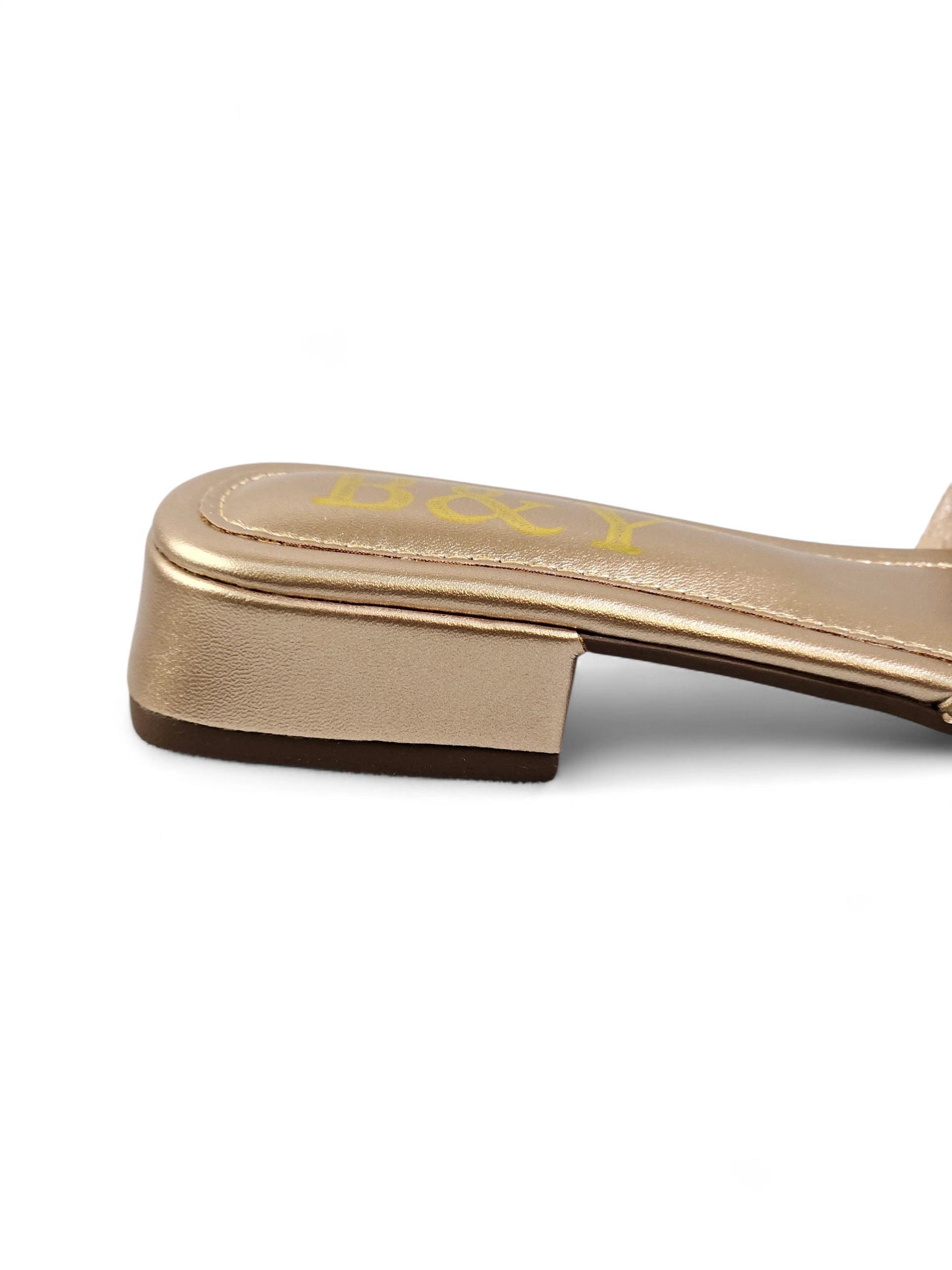 Sandália dourada artesanal com tiras entrelaçadas e cristais cintilantes.