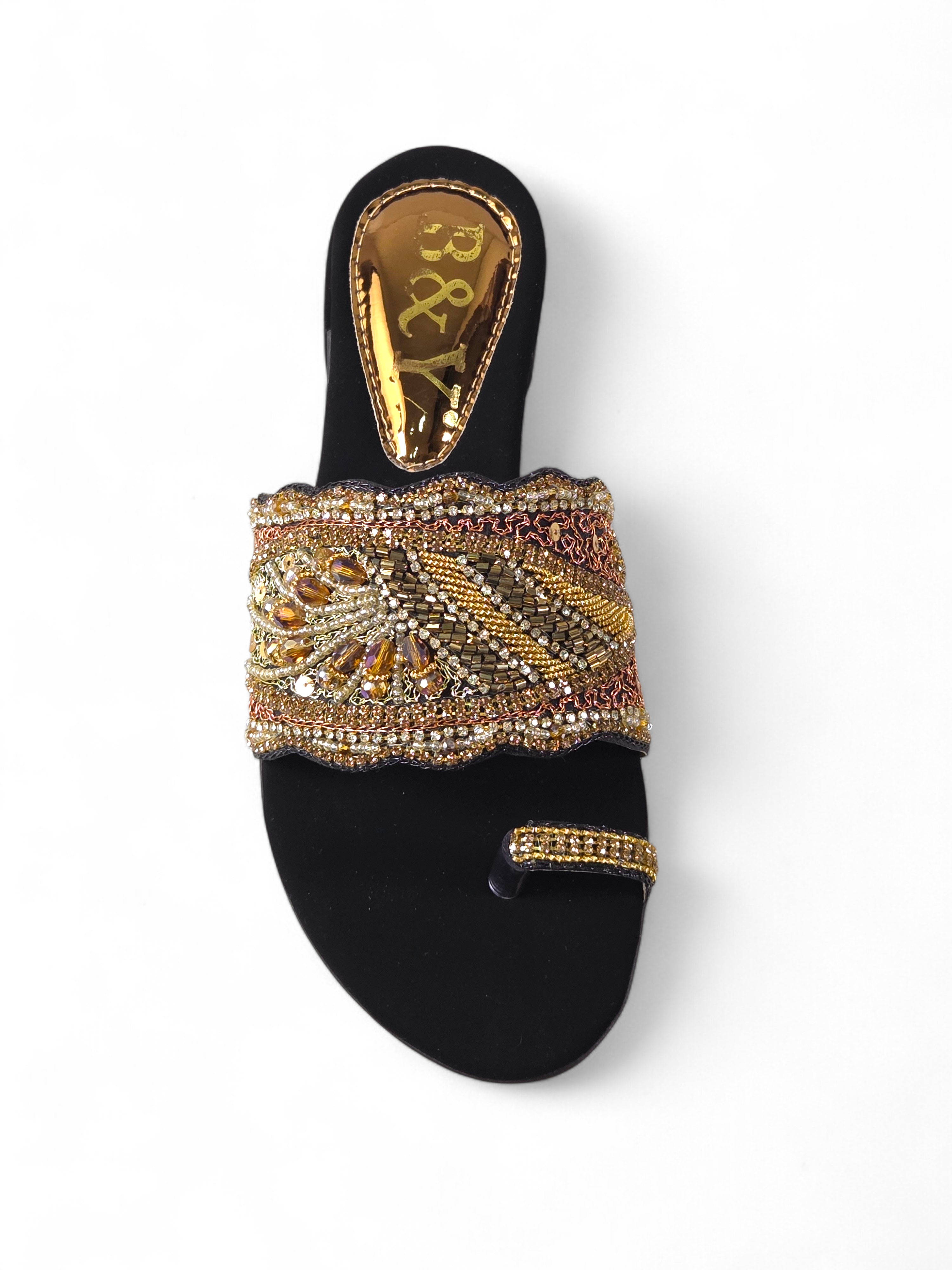 Sandália artesanal B&Y preta com pala bordada à mão, aplicação de cristais dourados, salto baixo e acabamento sofisticado, em fundo branco.