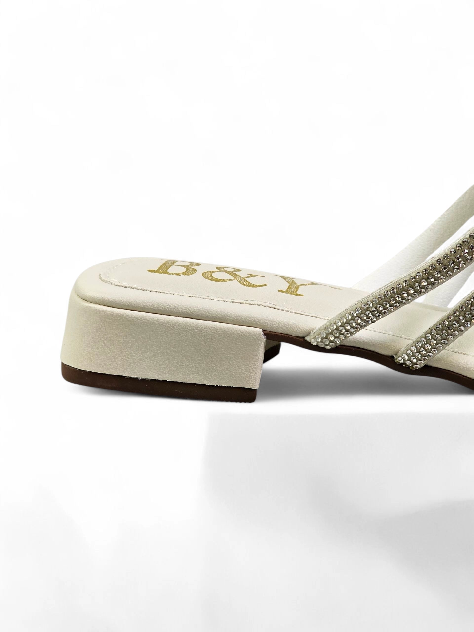 Sandália branca artesanal com tiras entrelaçadas e cristais brilhantes.