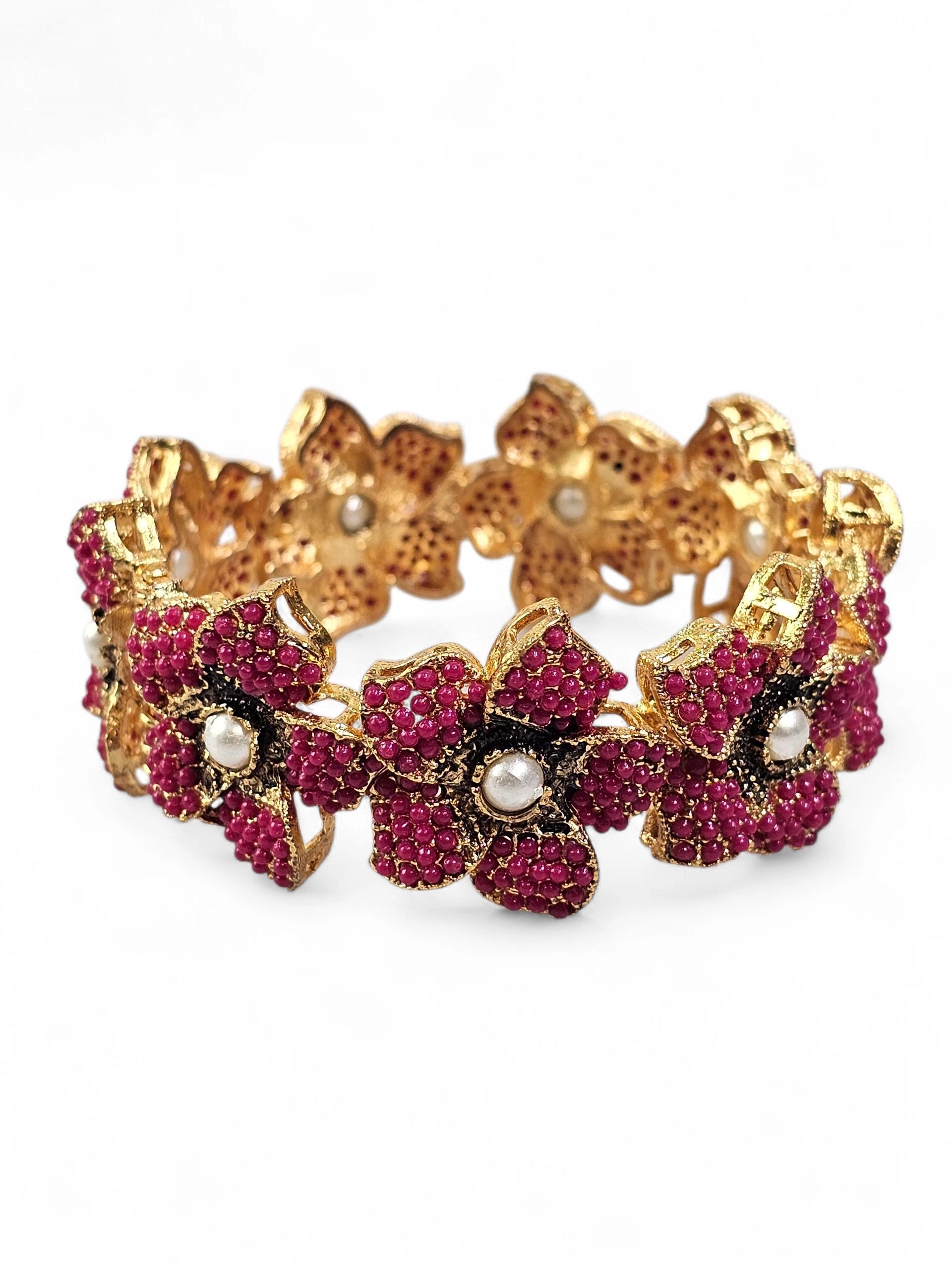 Bracelete floral artesanal B&Y com flores rosa-rubi, detalhes dourados e pérolas centrais.